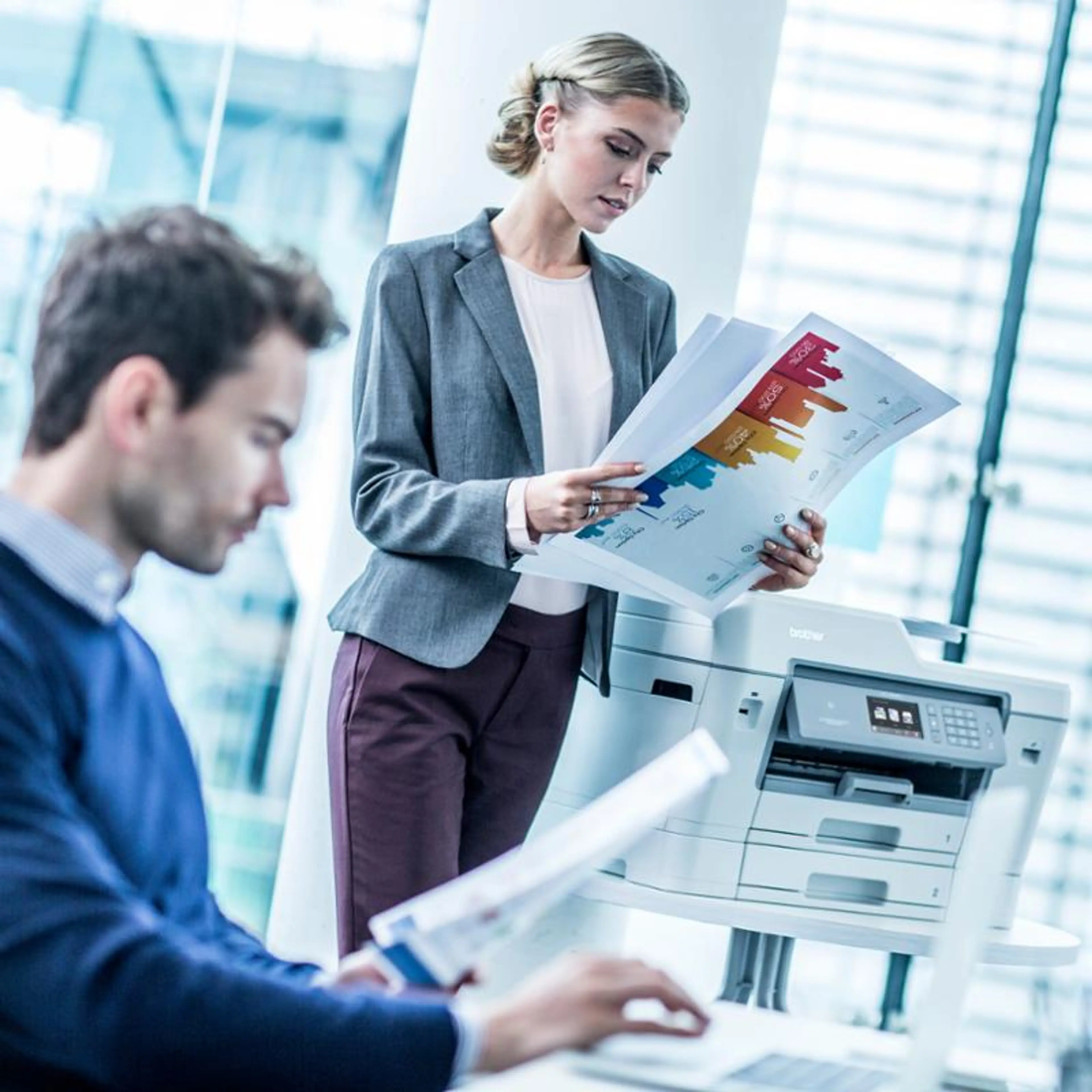 Mann og dame ved printer i kontorlandskap