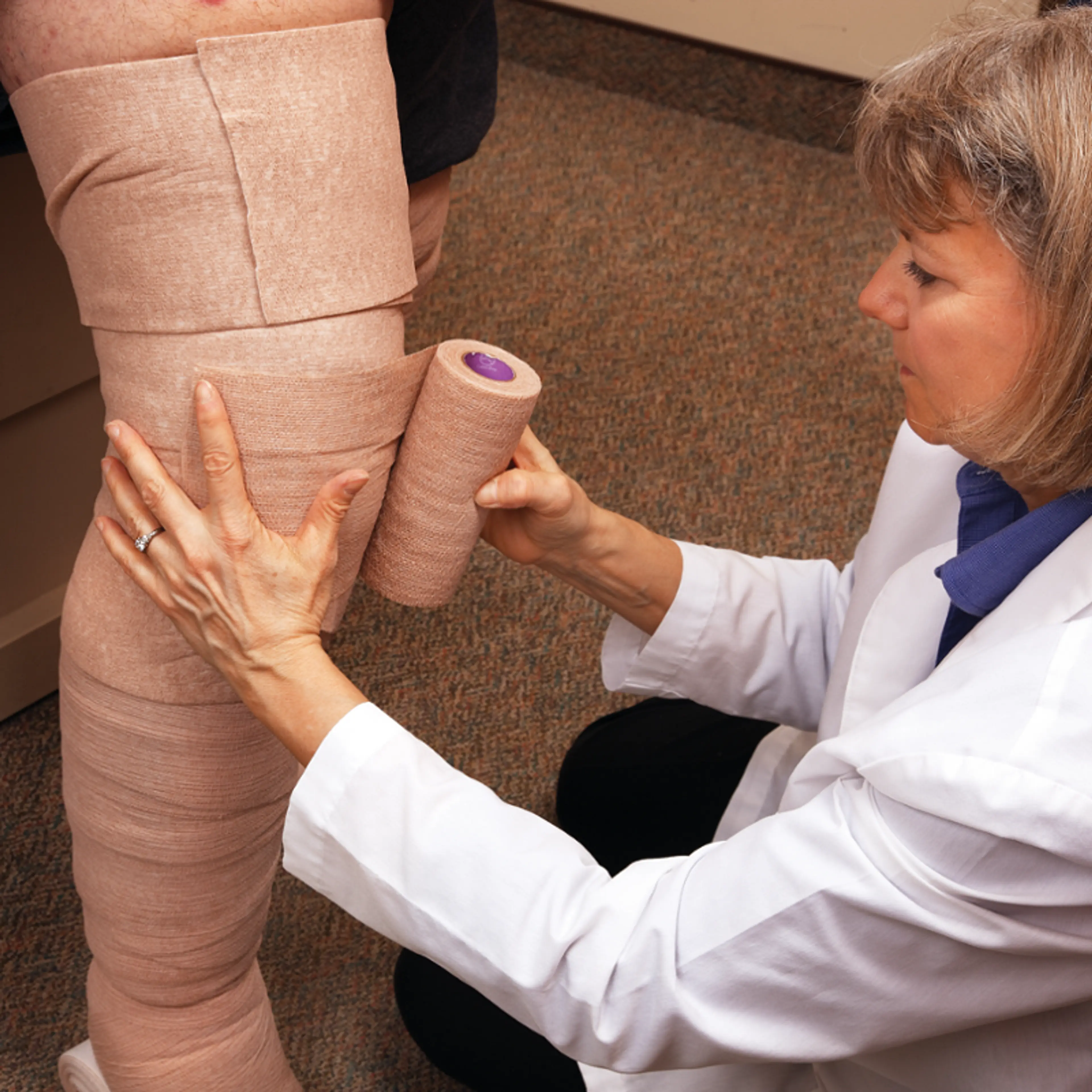 Lege som setter på Coban2 sårbandasje på pasient