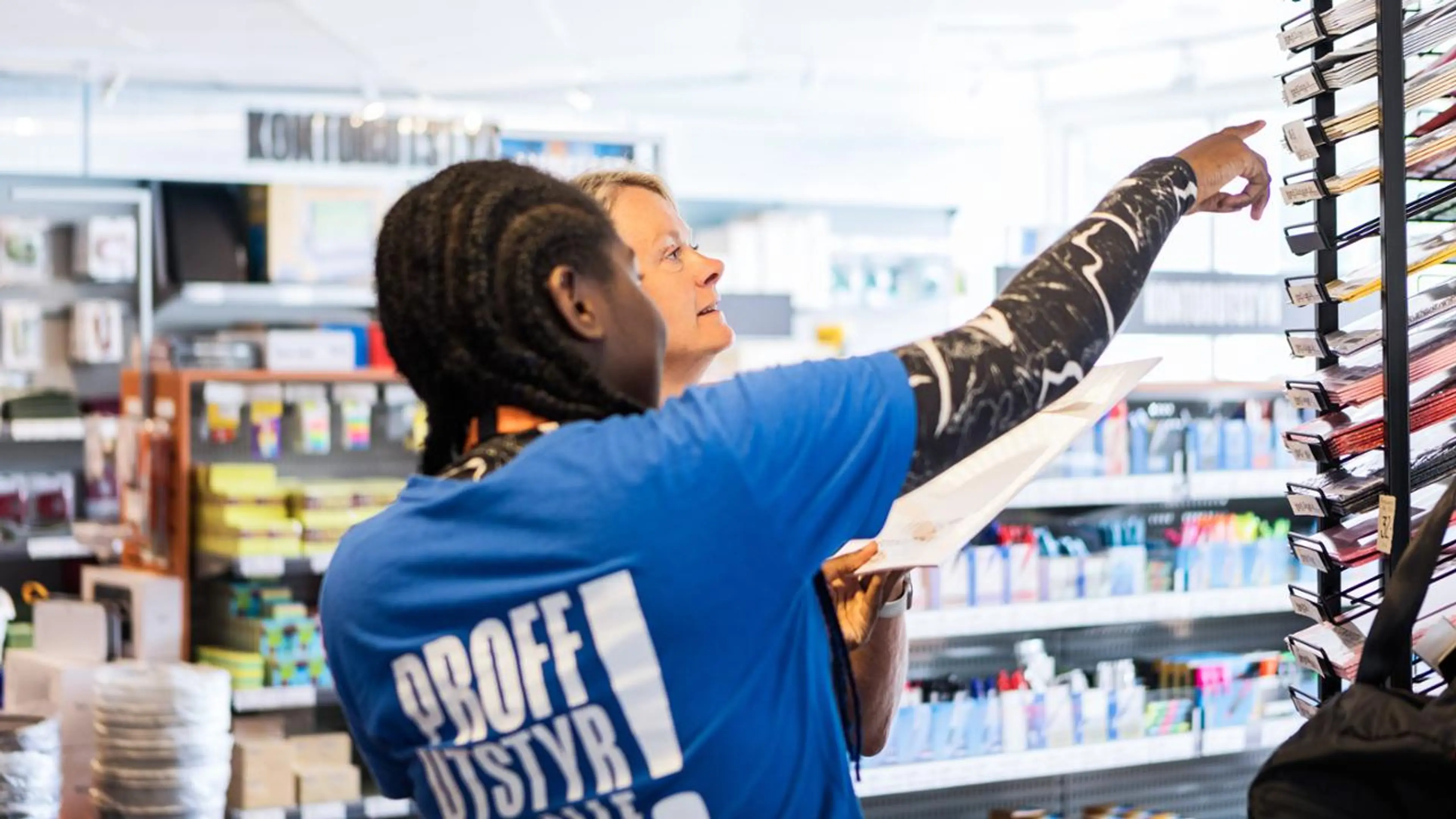 Butikkansatt viser kunde varer i butikk