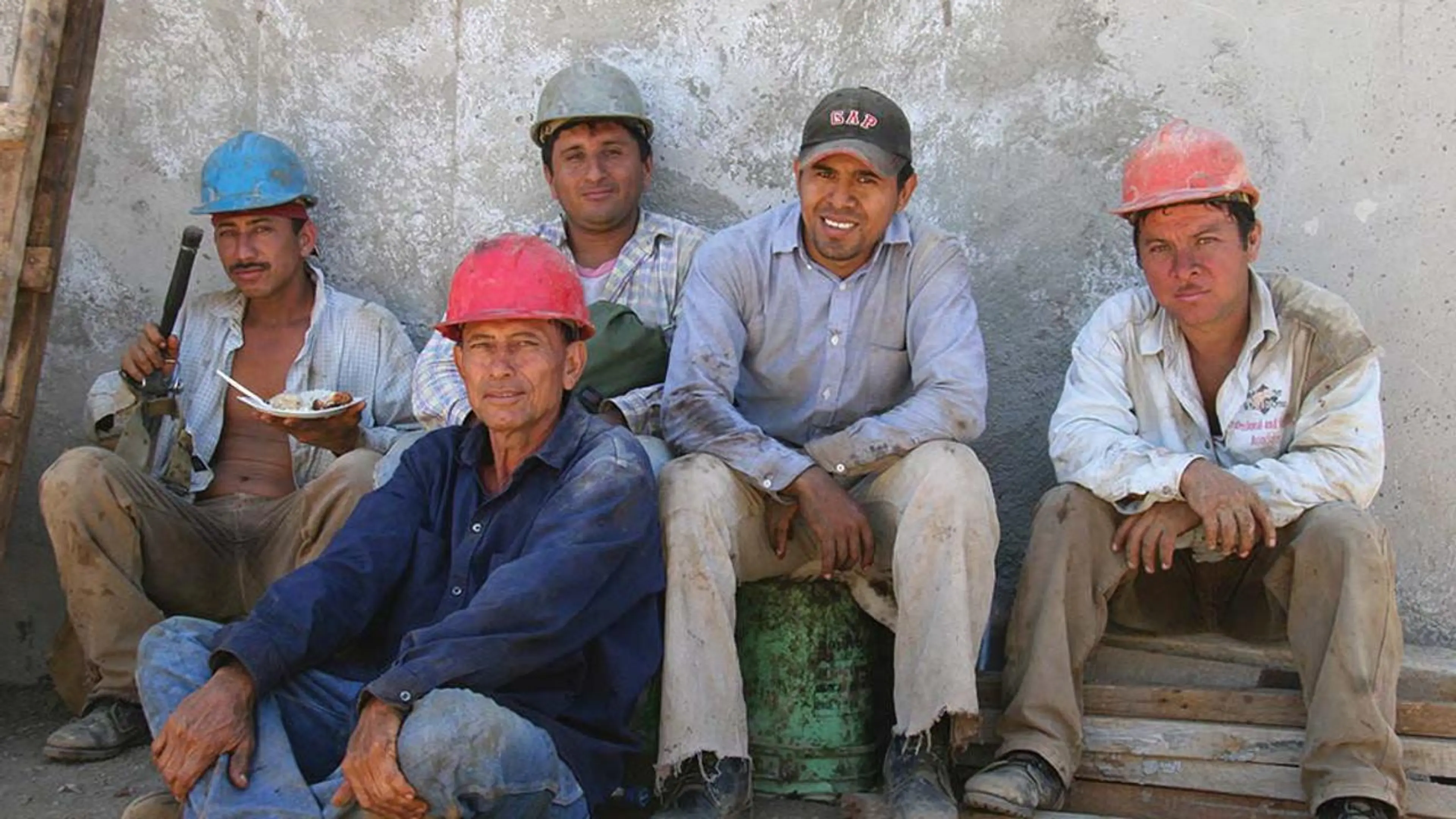 Arbeidere sitter langs vegg