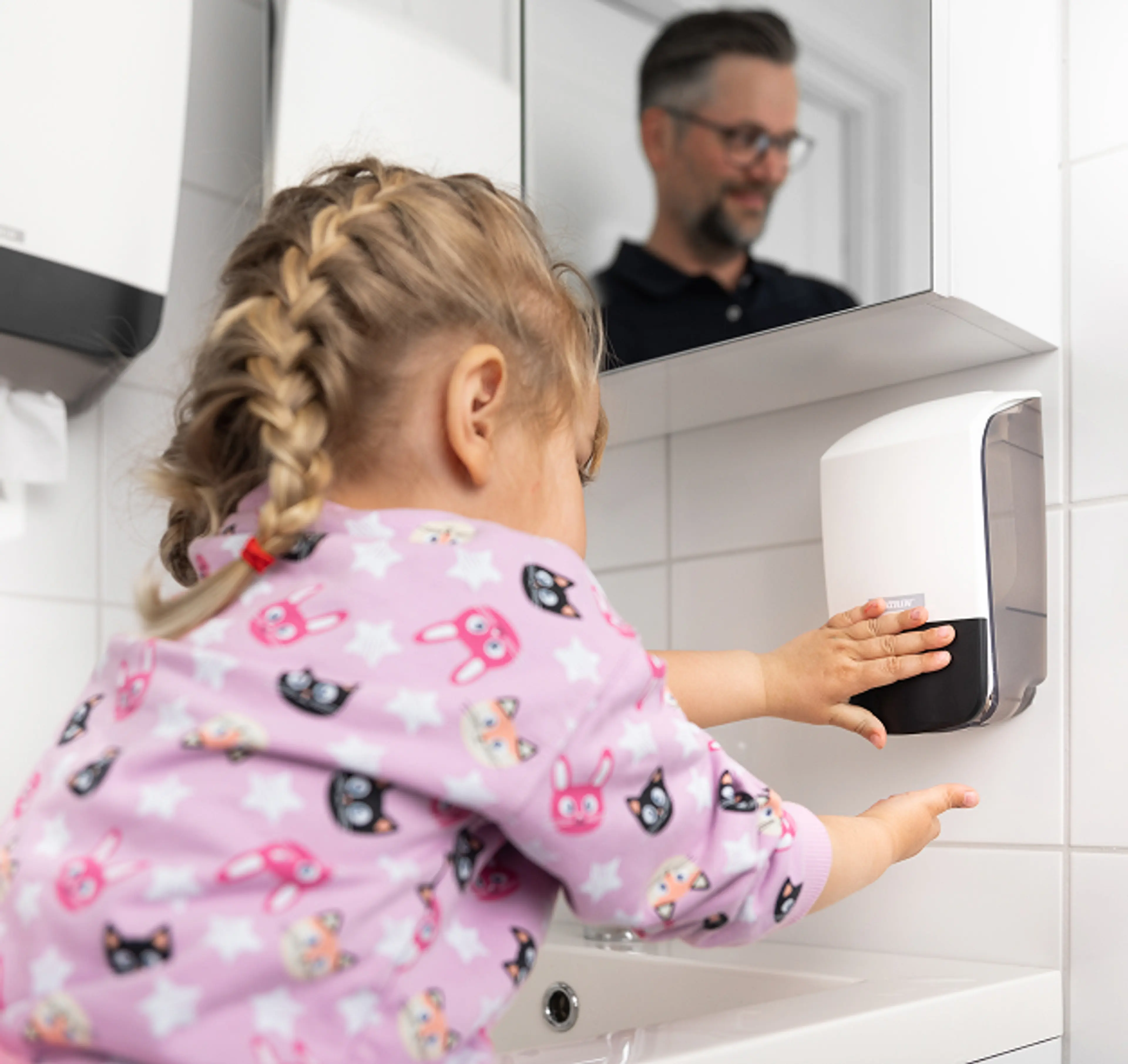 Jente som bruker Katrin såpedispenser på toalettrom