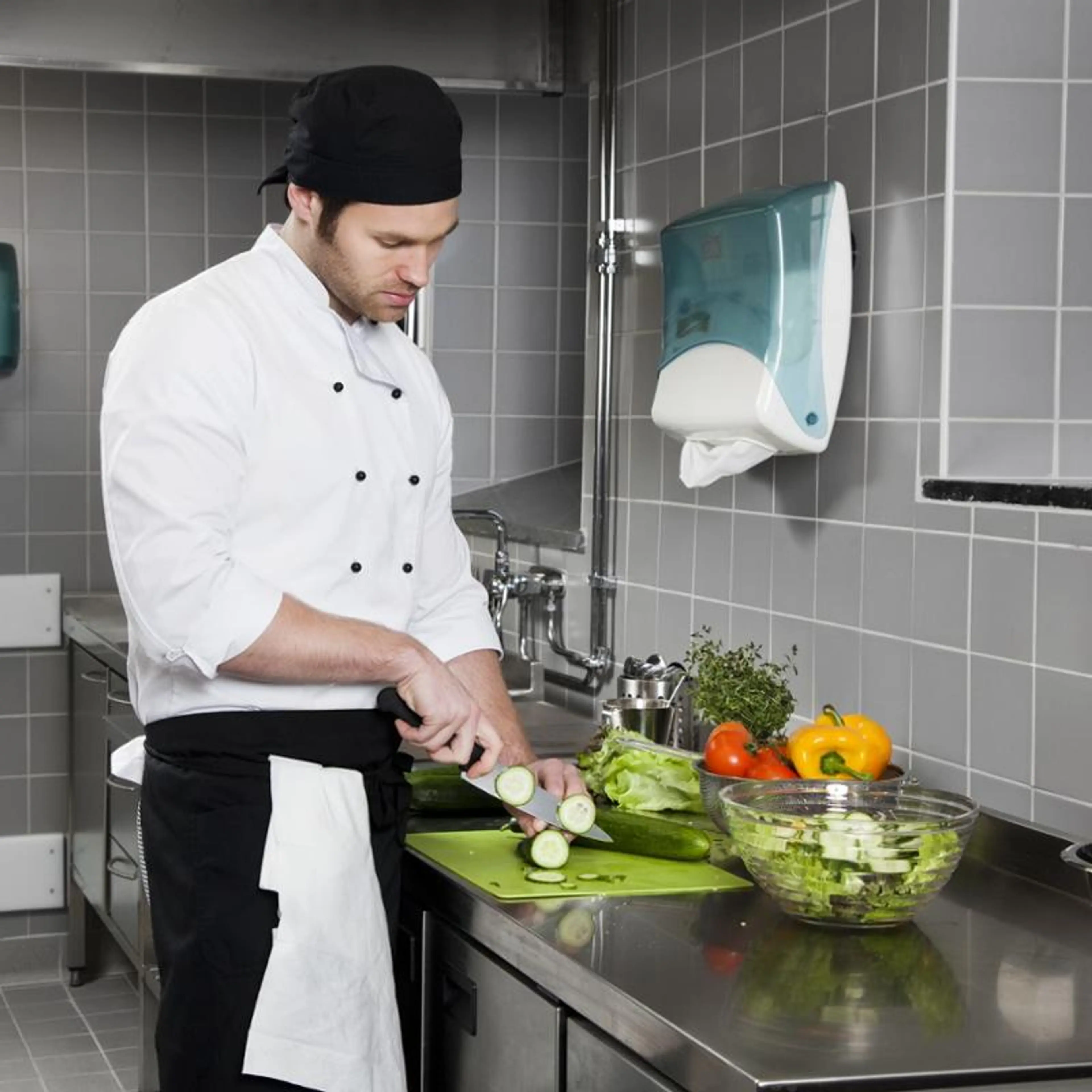 Kokk skjærer grønnsaker på kjøkkenbenk