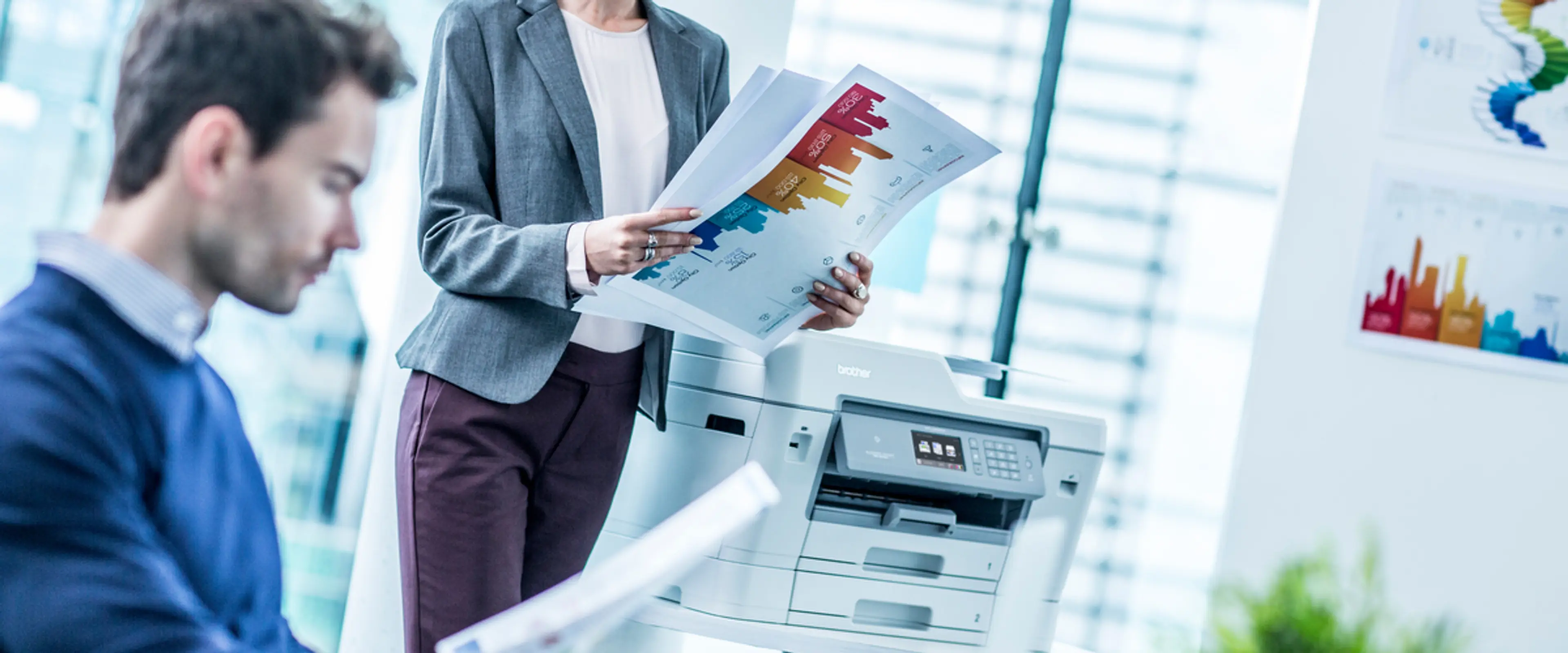 Mann og dame ved printer i kontorlandskap