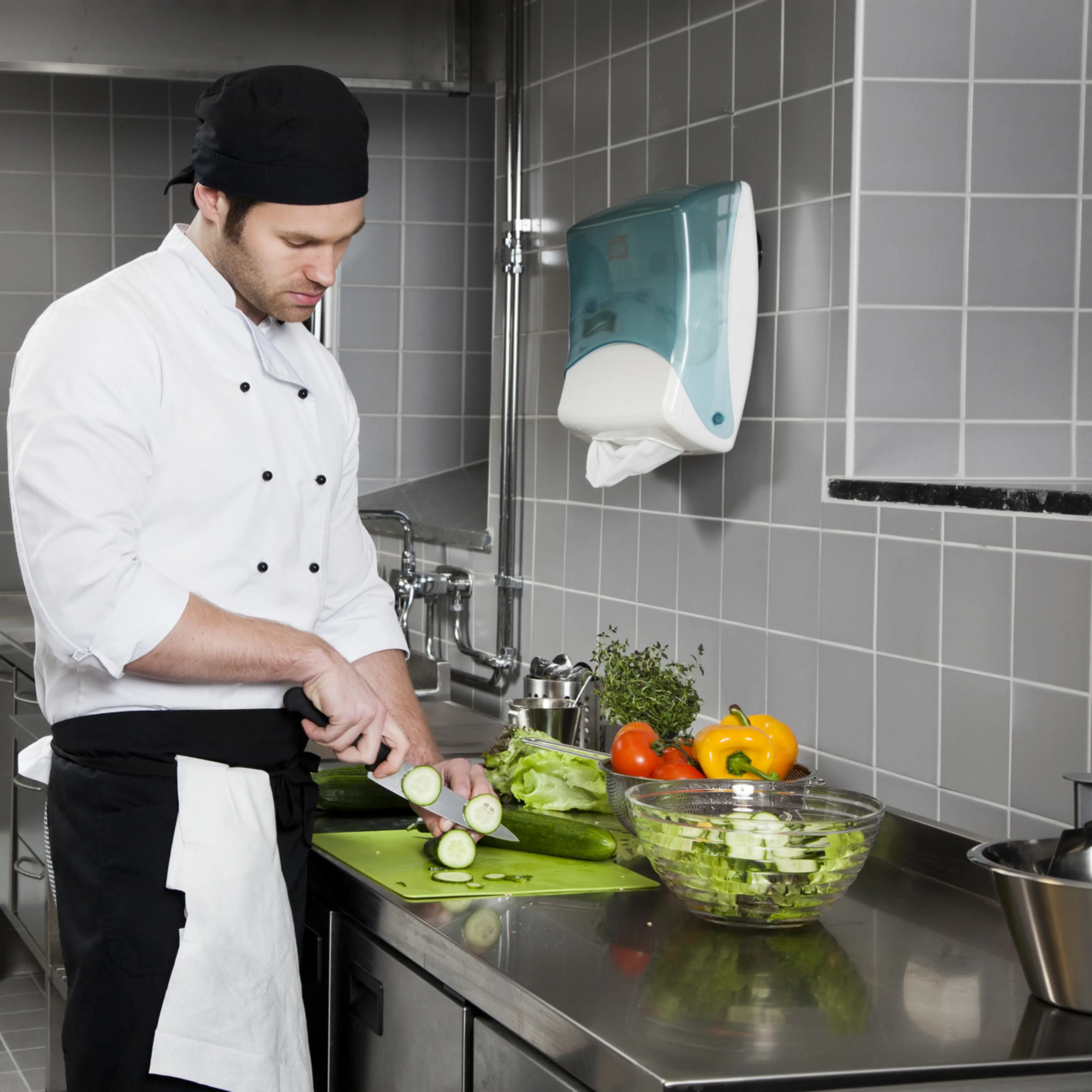 Kokk skjærer grønnsaker på kjøkkenbenk