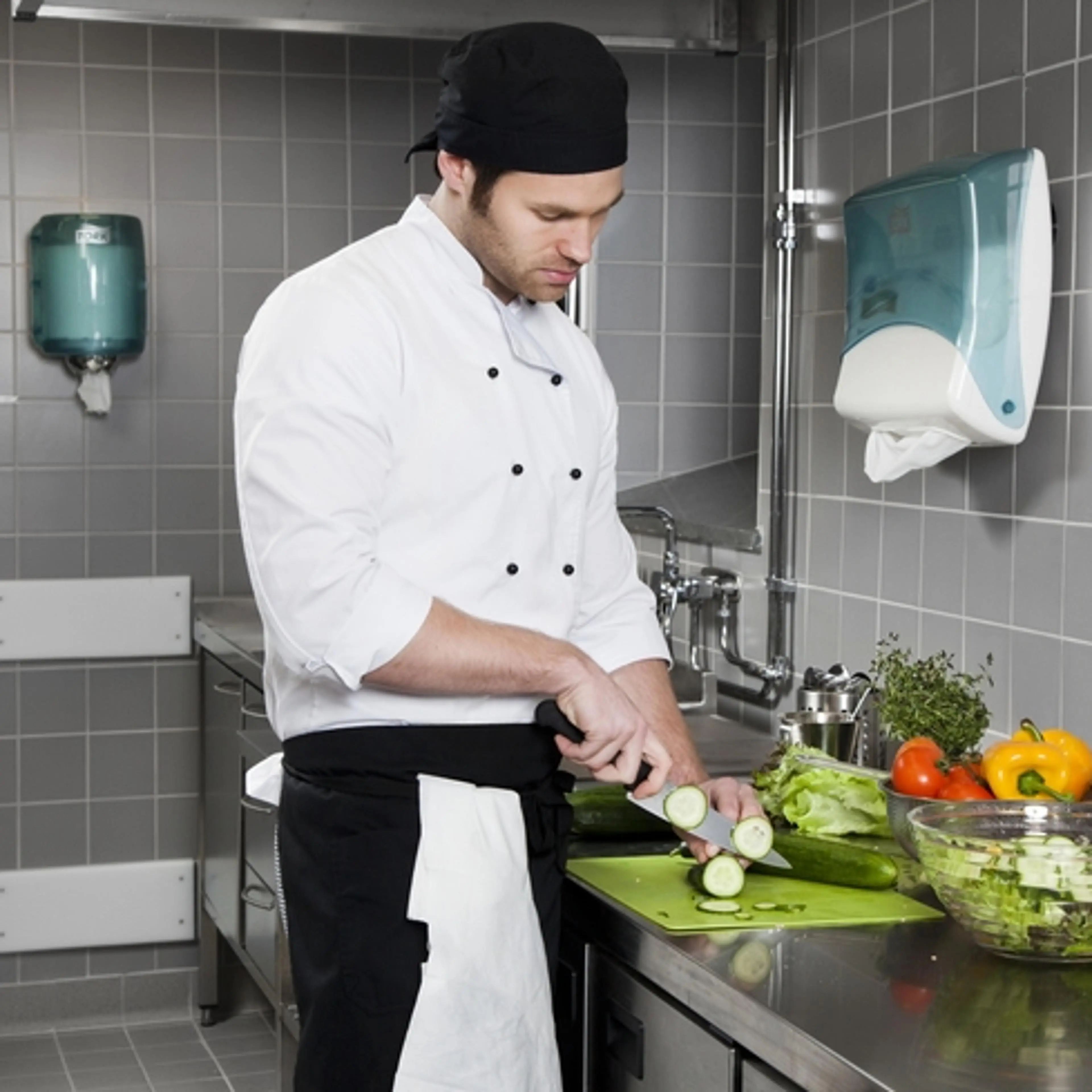 Kokk skjærer grønnsaker på kjøkkenbenk