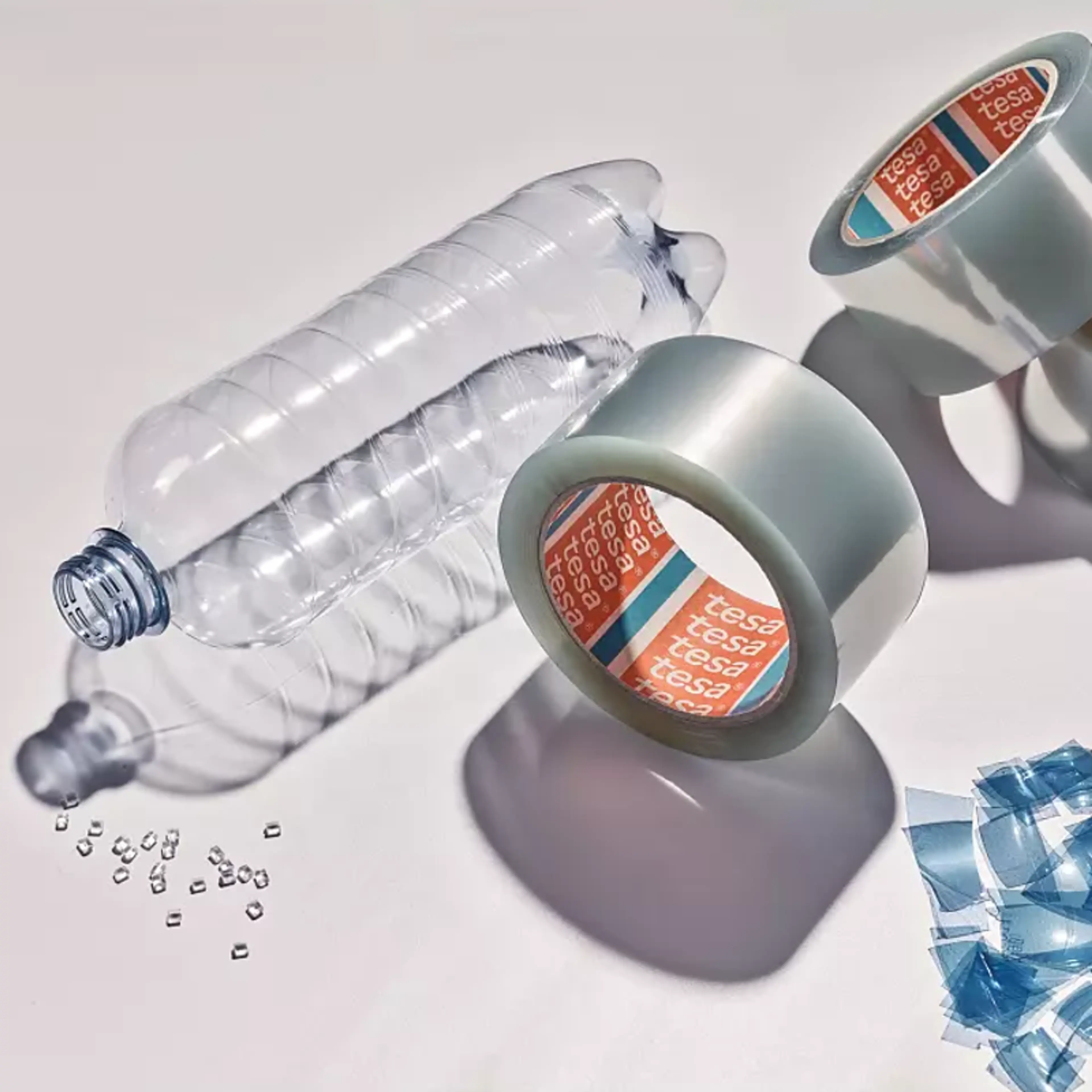 Tesa PCR-PET tape ved siden av tomflaske og PCR-PET pellets
