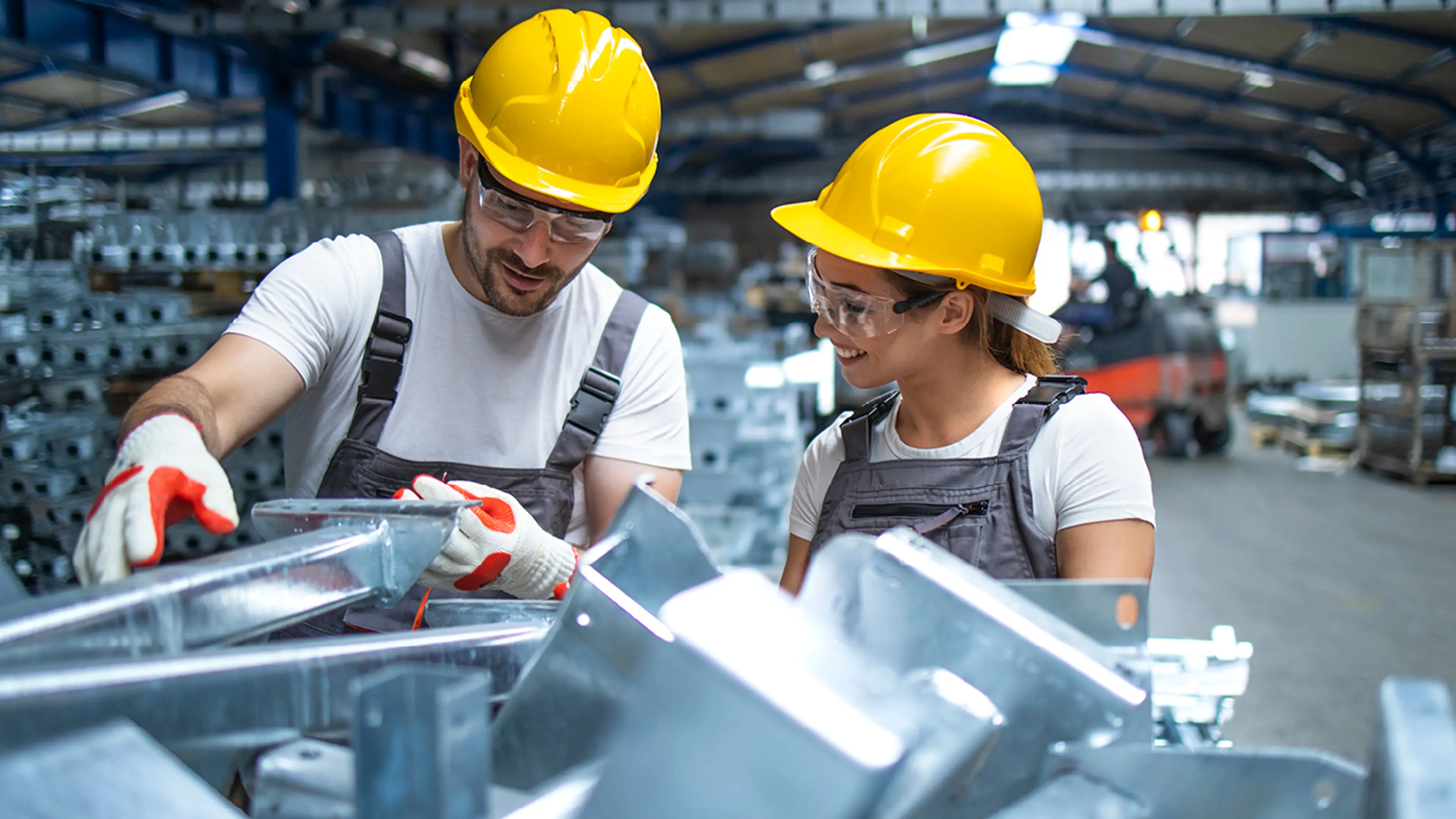 Personer i fabrikk ser på aluminium