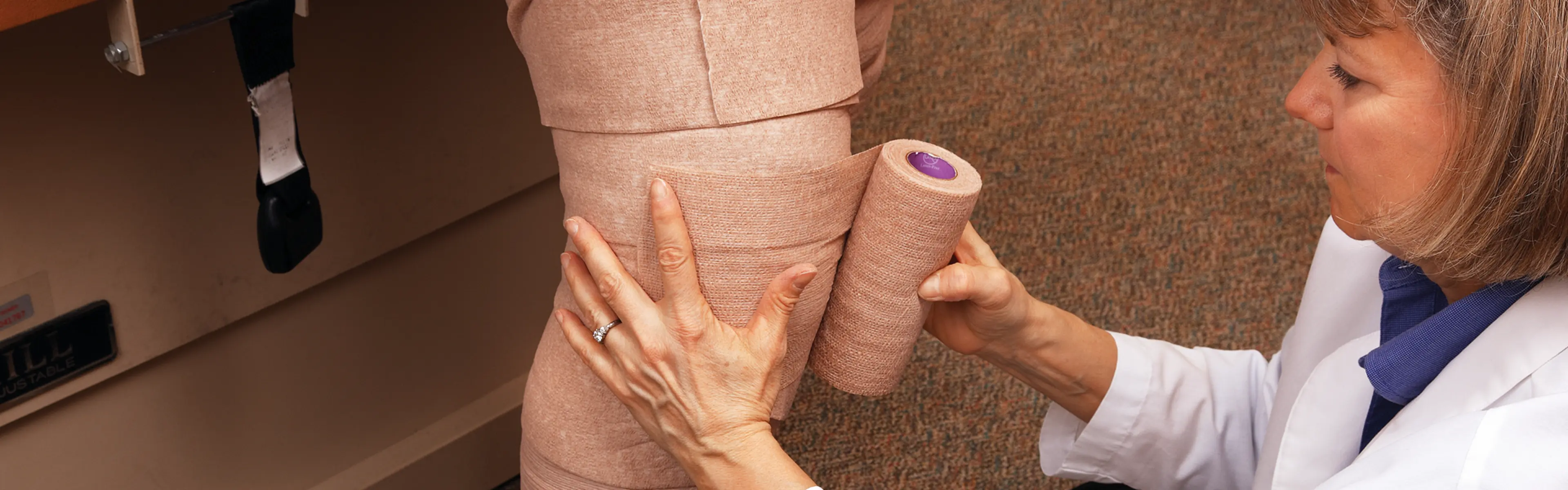 Lege som setter på Coban2 sårbandasje på pasient