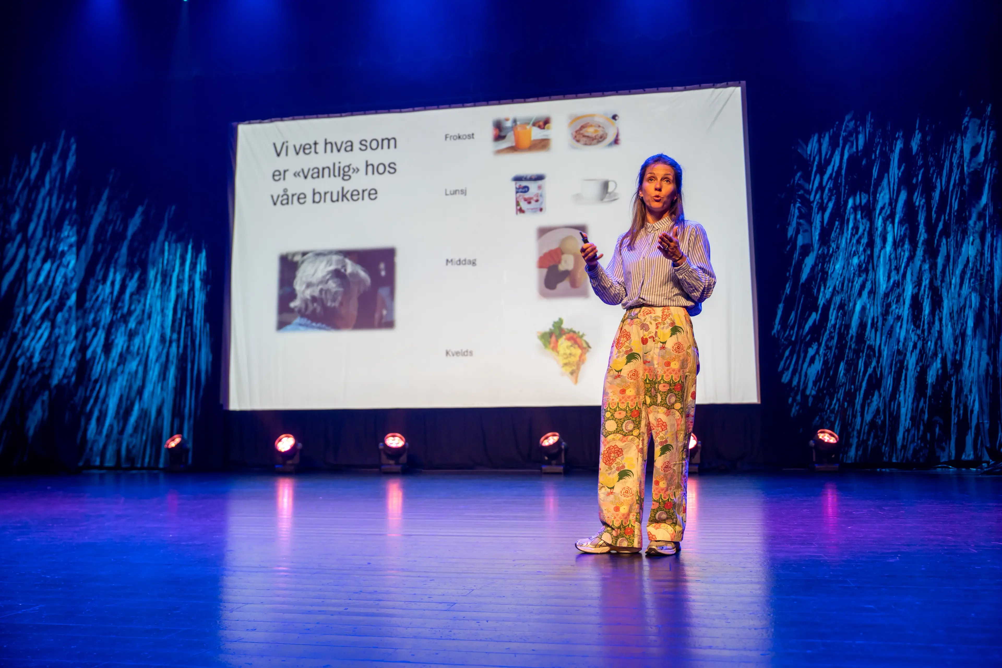 Kristine Nordkvelle på scenen med presentasjon i bakgrunnen