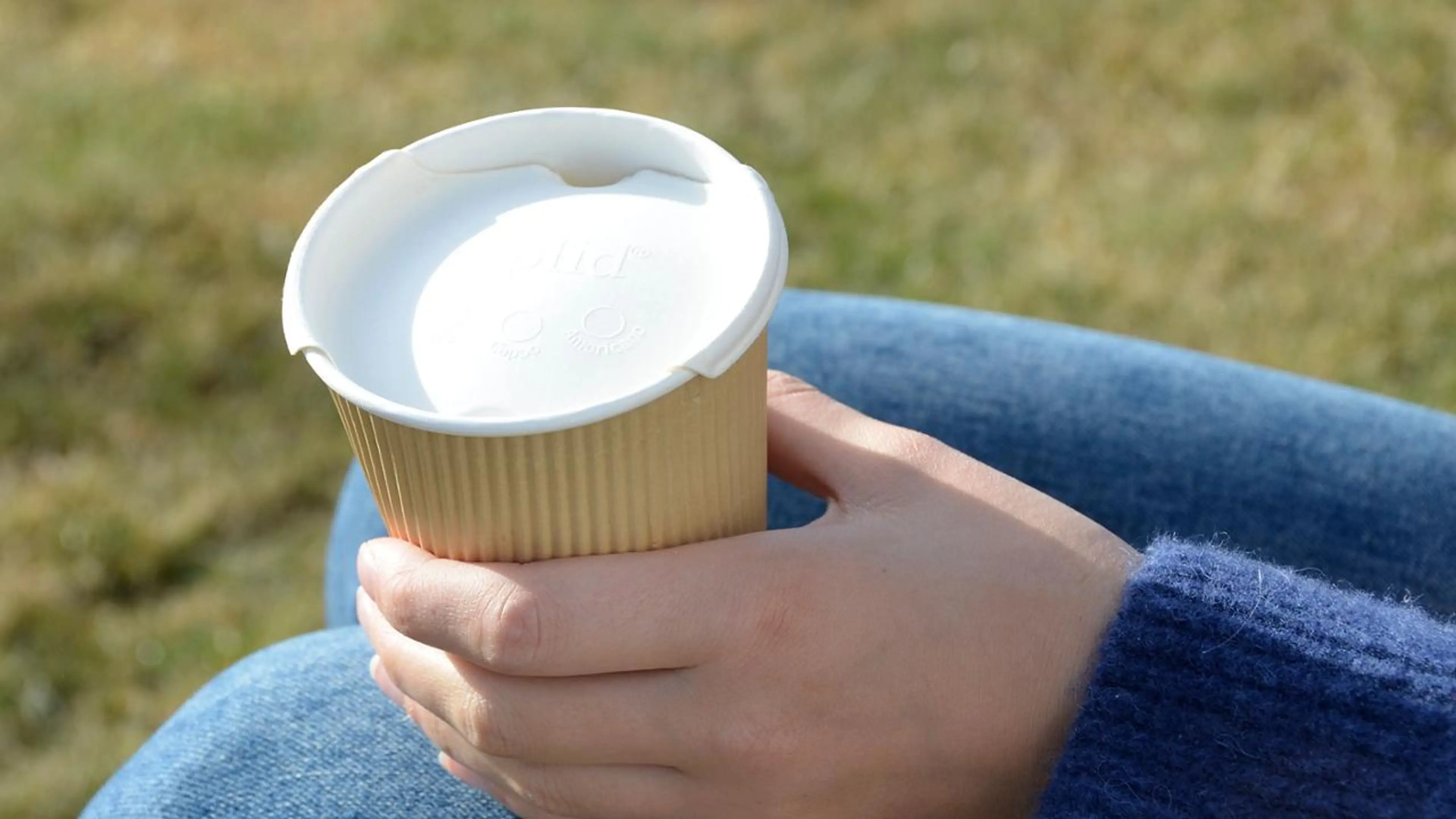 Mann som holder engangskopp med Liplid-lokk