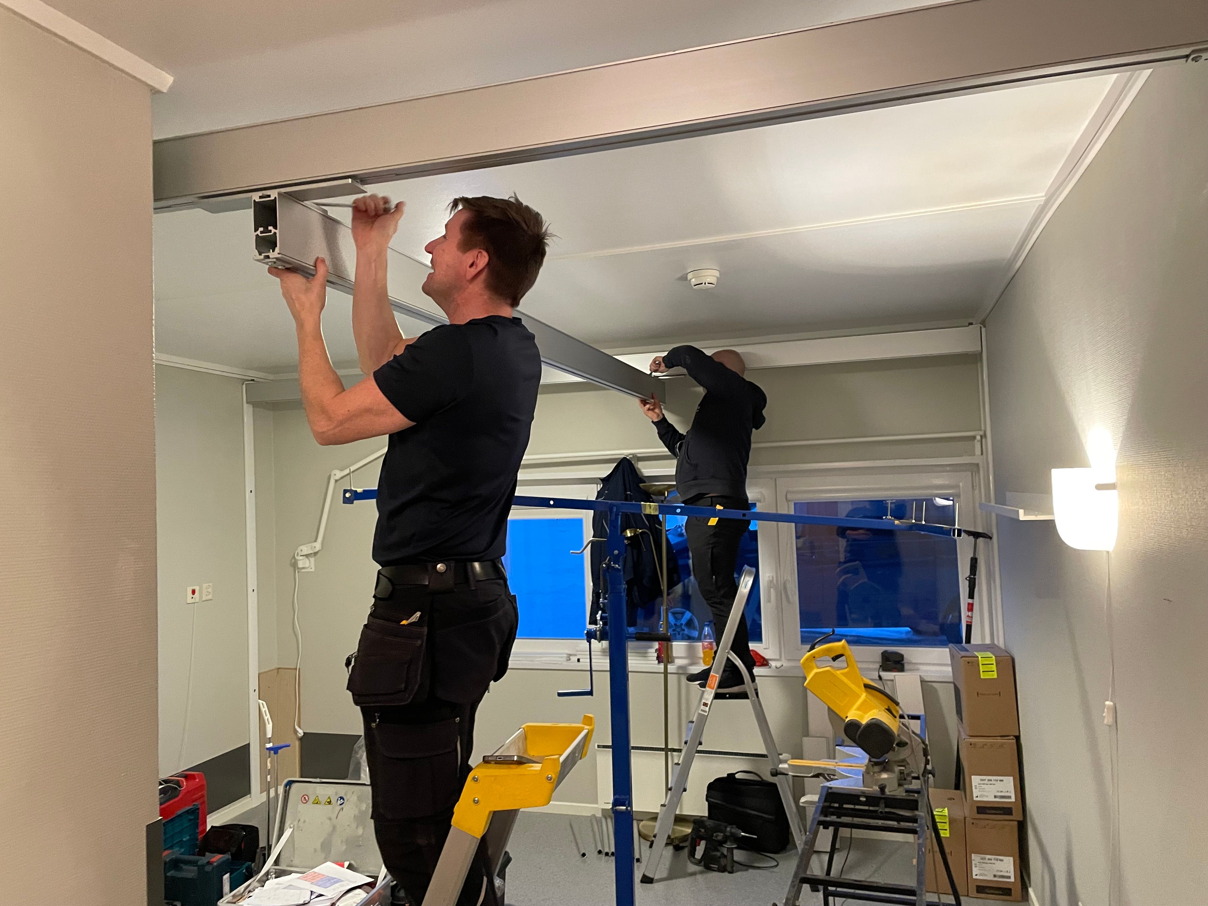 Teknikere installerer skinner til takheis