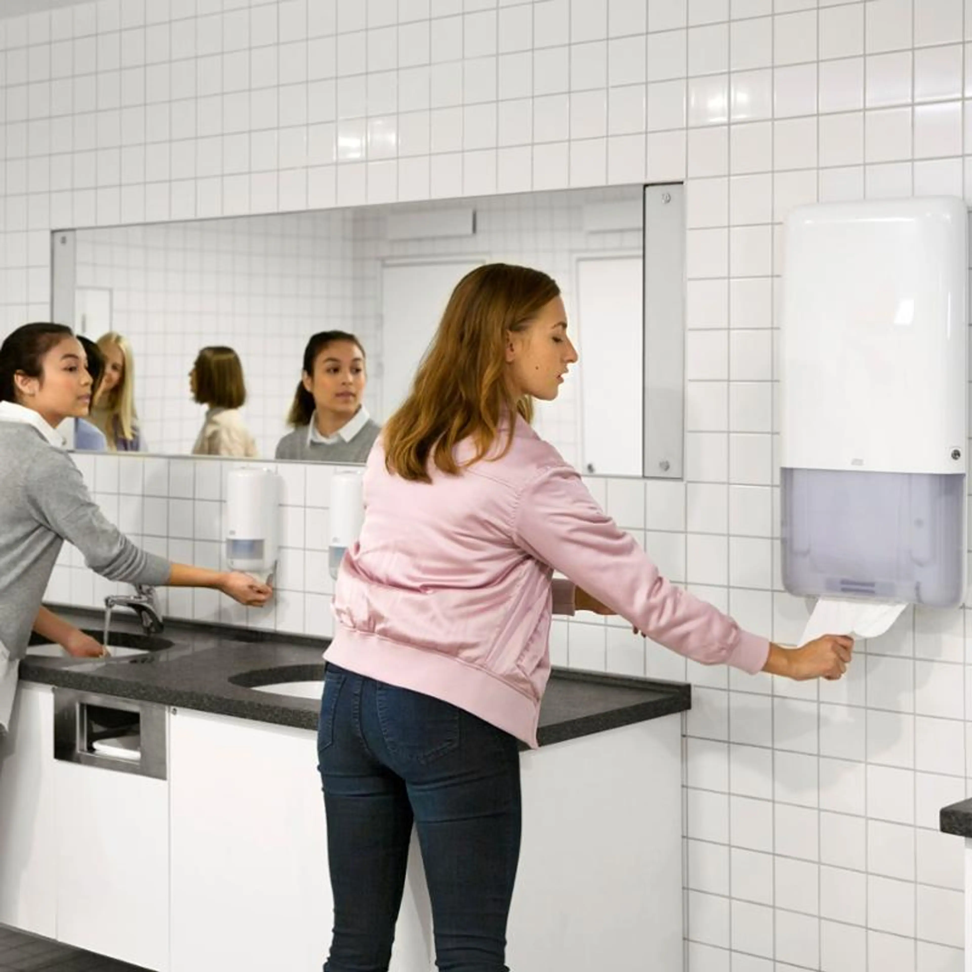 Kvinne som bruker tørkepapir på et toalettrom