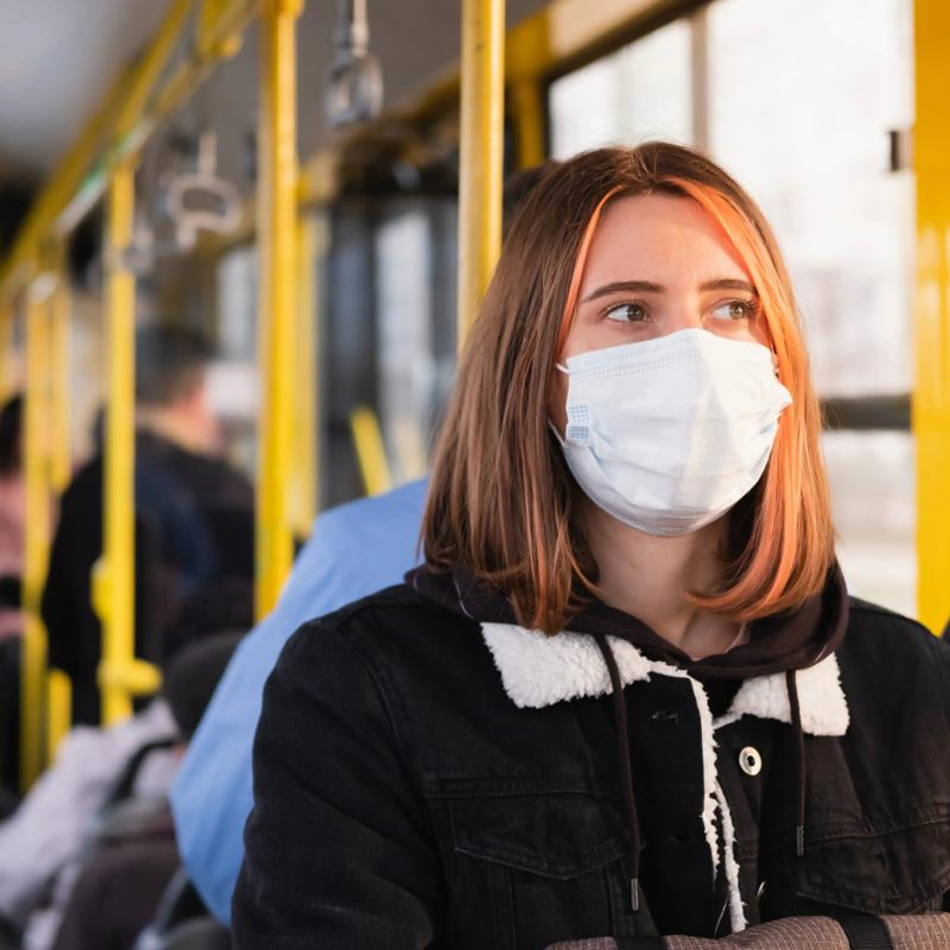 Kvinne på buss som bruker munnbind