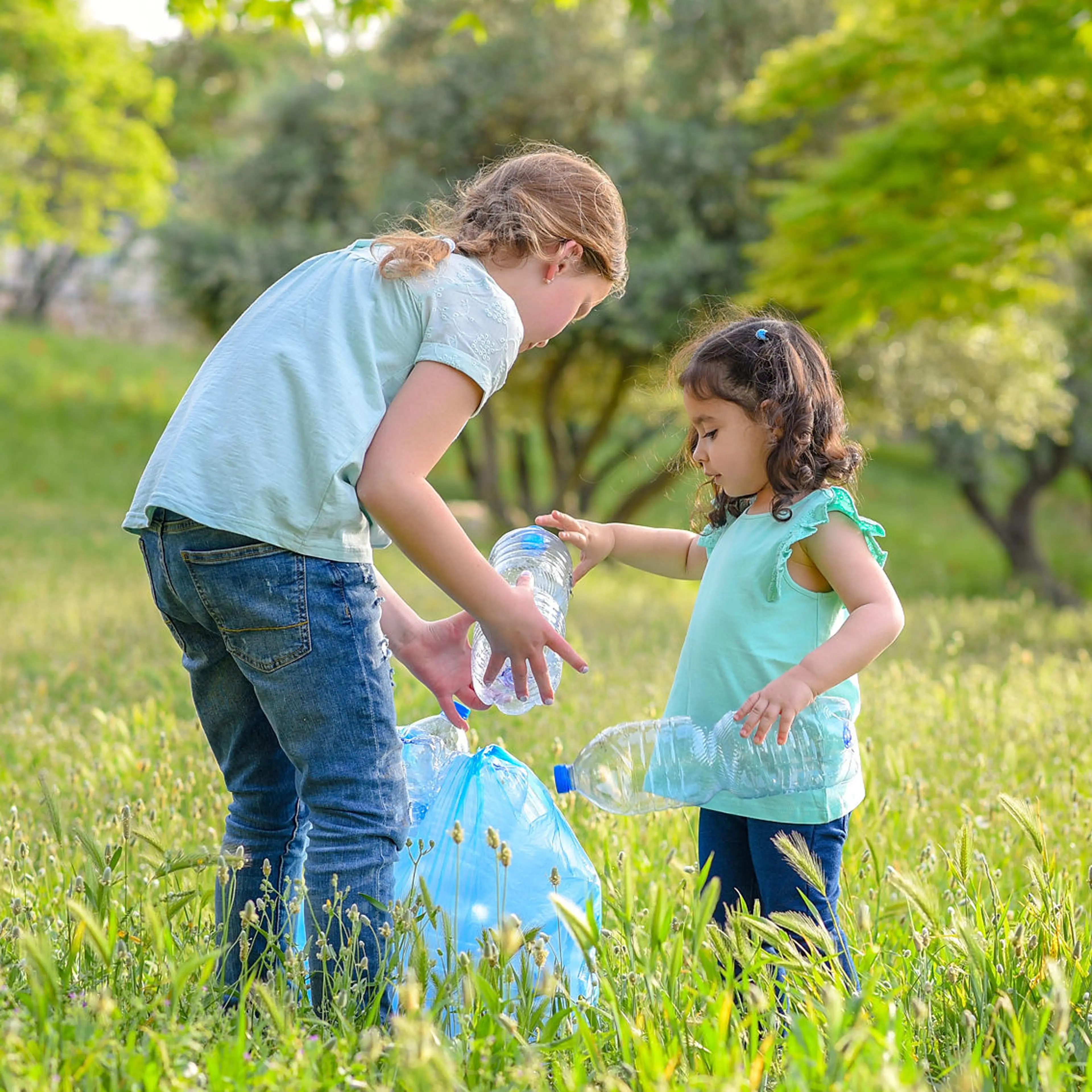 To jenter plukker plast i skogen