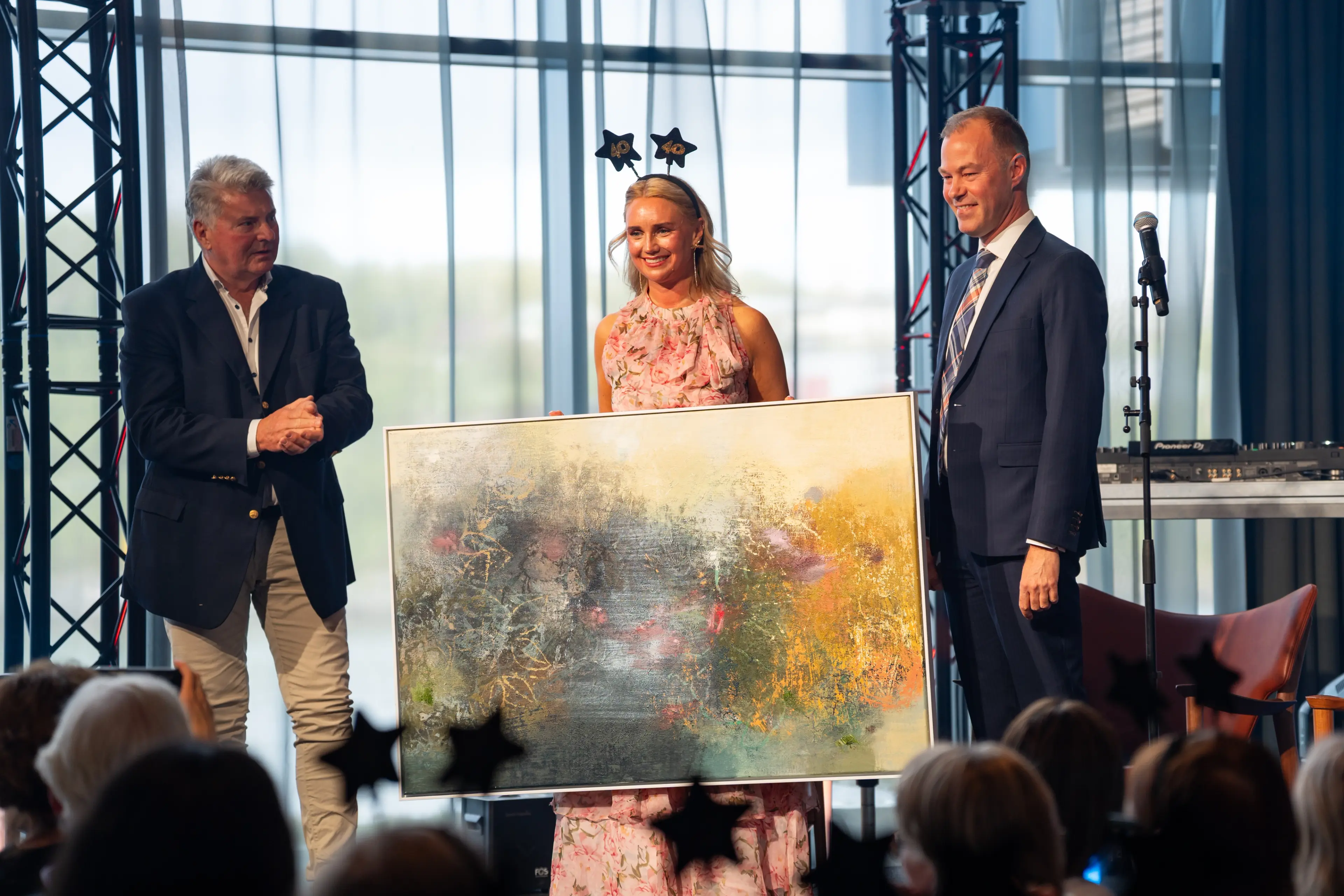 Camilla Skog Rodal viser frem et stort, fargerikt maleri på scenen under Helsedagene 2025.