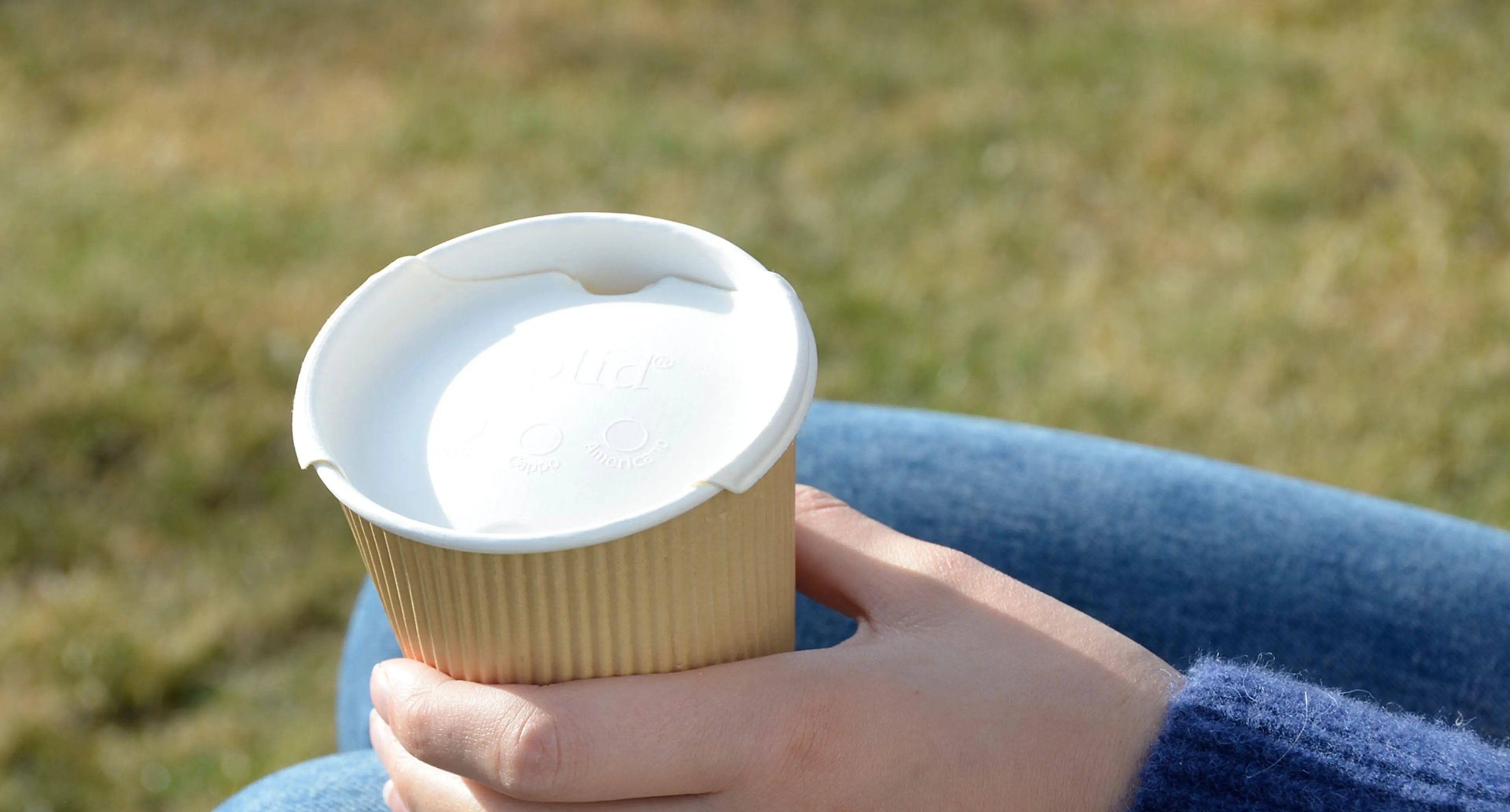 Person som holder en kaffekopp med lokk fra Liplid