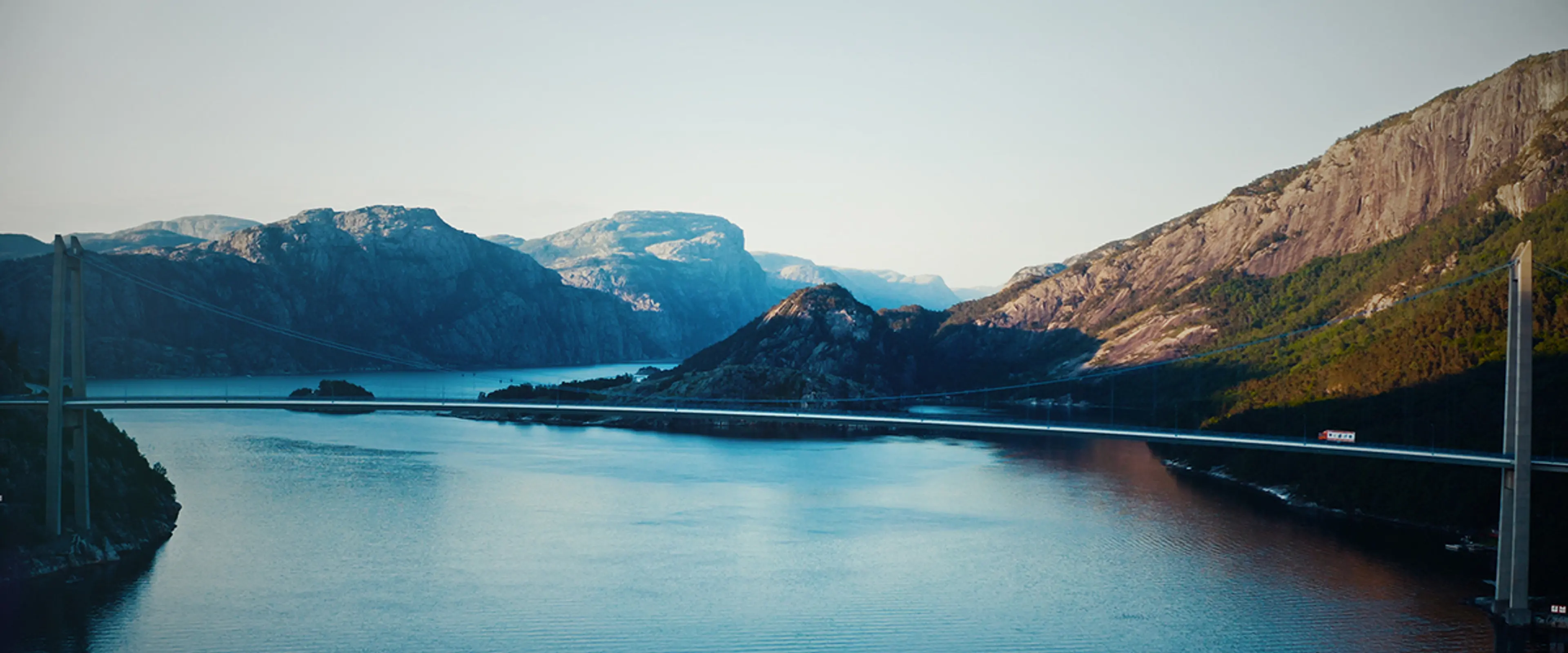 Bro over en fjord med fjell i bakgrunnen