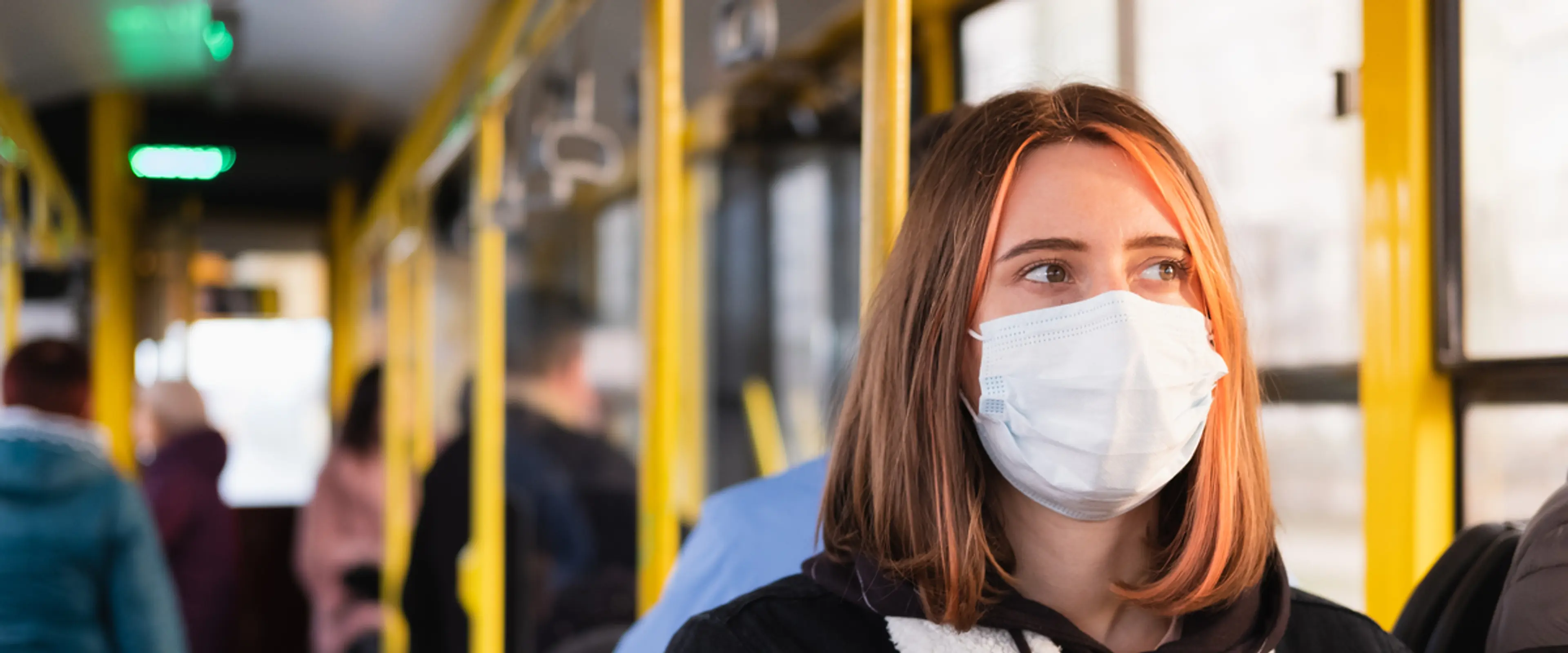 Kvinne på buss som bruker munnbind