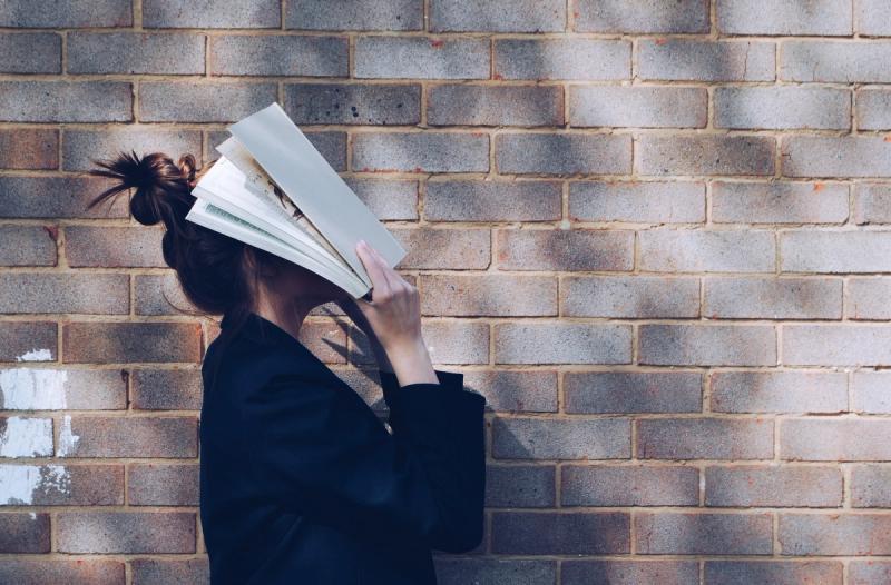 Kvinne som skjuler ansiktet sitt i en bok
