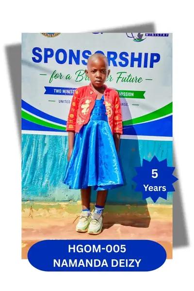Girl in a blue dress with a red jacket standing before a sponsorship banner