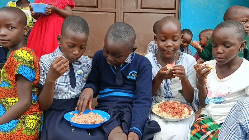 Children sitting outside eating rice and beans from bowls