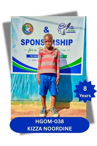 Boy in a striped shirt and blue shorts standing before a sponsorship banner