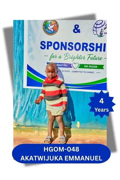 Toddler boy in a striped sweater and cream shorts standing before a sponsorship banner