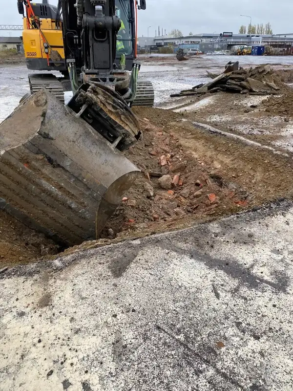 Grävskopa som gräver i fyllnadsmassor med tegelrester