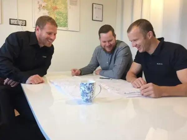 Tre medarbetare på ENRECON tittar på en karta vid ett bord
