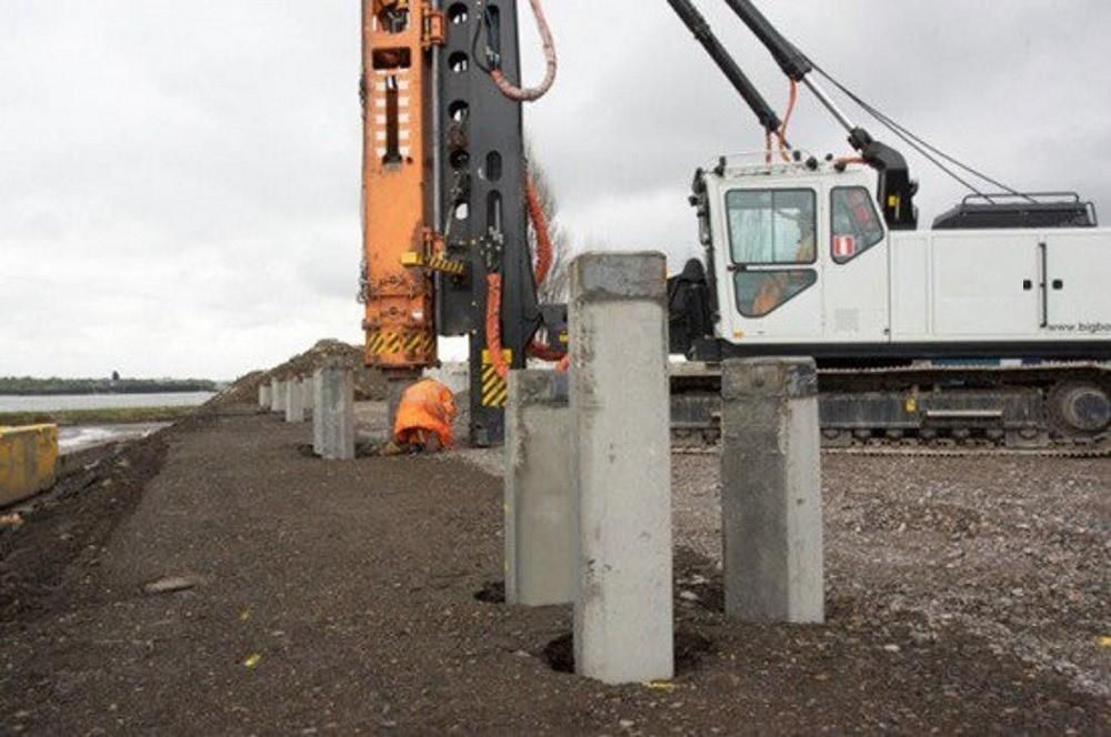 Precast concrete piles driven in a line alongside a crawler crane