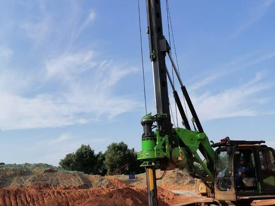 Rotary piling rig drilling a bored pile behind safety barriers
