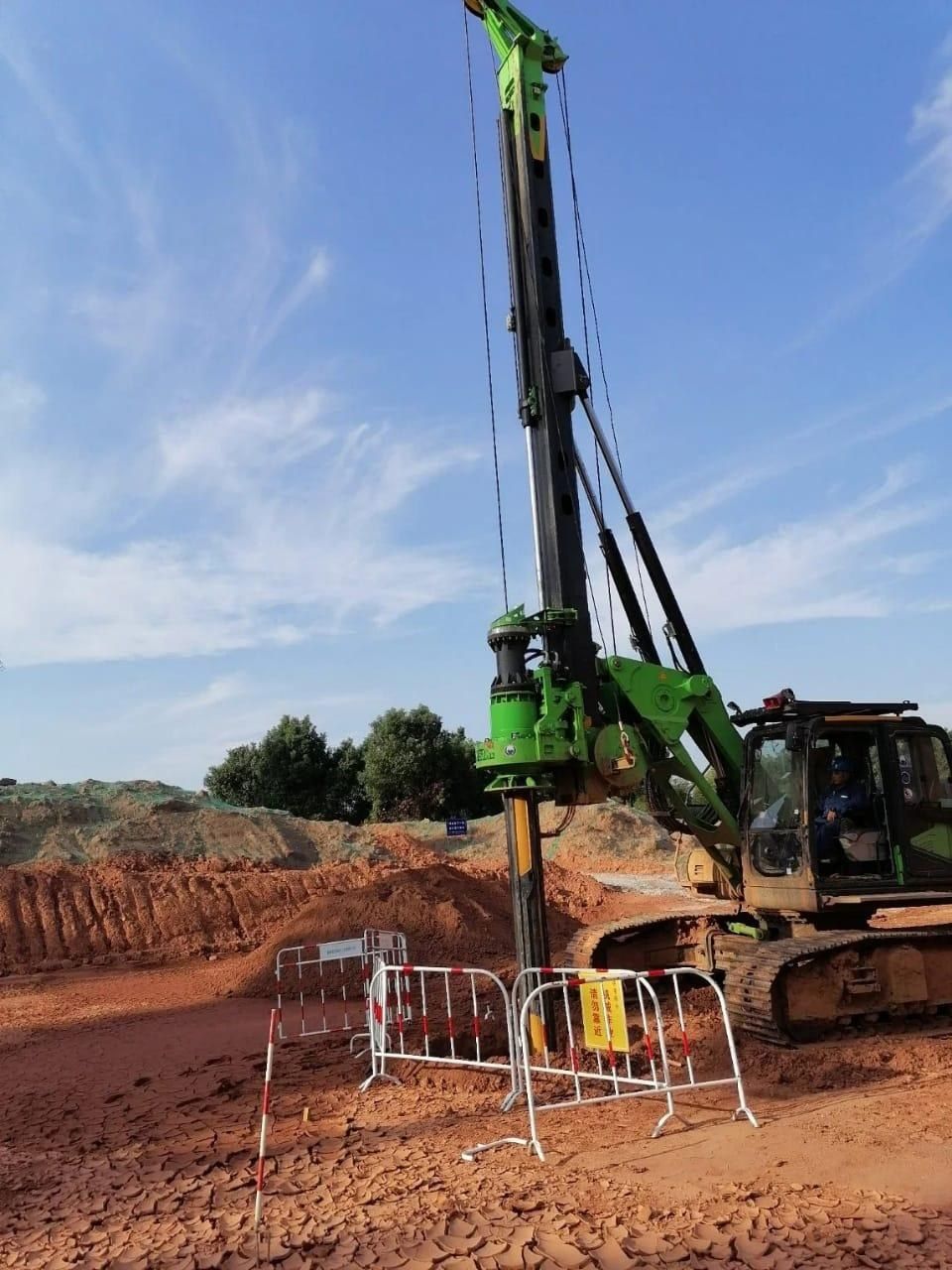 Rotary piling rig drilling a bored pile behind safety barriers