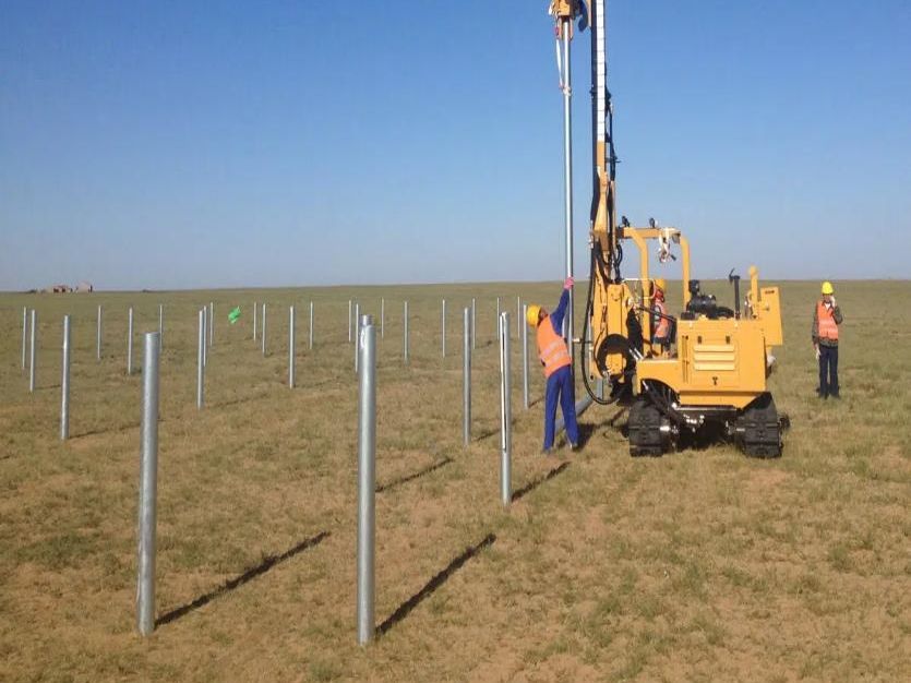 Pile driving machine installing rows of steel posts for a solar farm