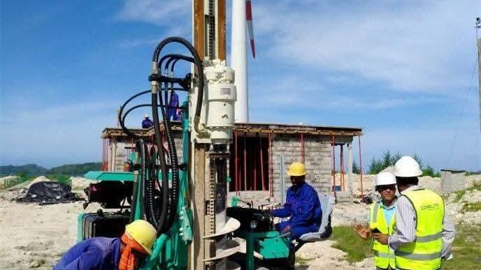 Crew operating a compact tracked drilling rig to install micro piles