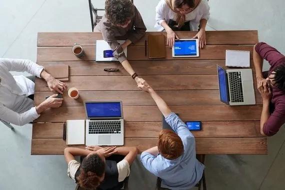 People shaking hands across table during meeting