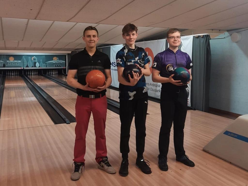 Tre bowlare med sina klot på banan, i bakgrunden målningen av Jakobstads gamla trähus