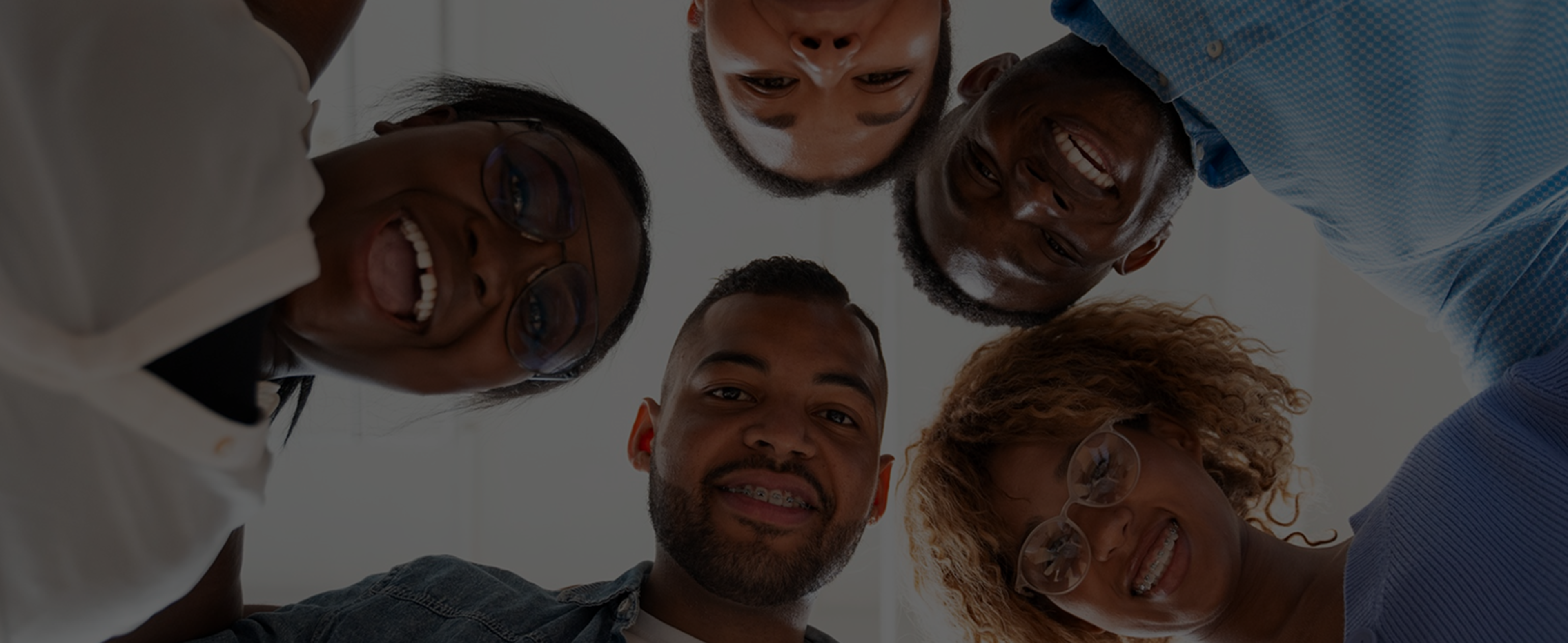 Five people in a huddle looking down into the camera, the Ghost wordmark across them.