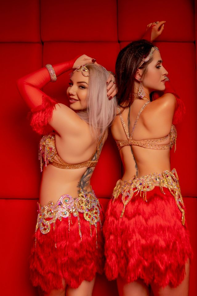 Tancerki Wahatan w czerwonych kostiumach bellydance z piórami i złotymi zdobieniami