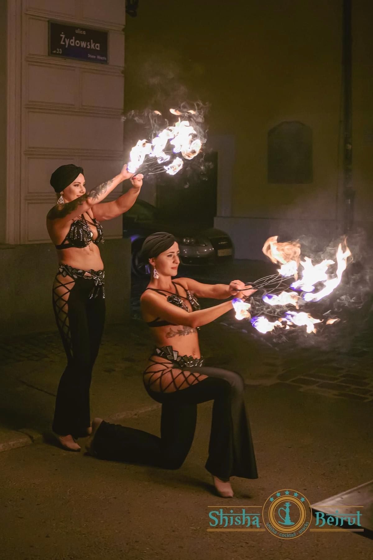 Duet Wahatan wykonuje pokaz ogniowy na ulicy — obie tancerki z płonącymi rekwizytami