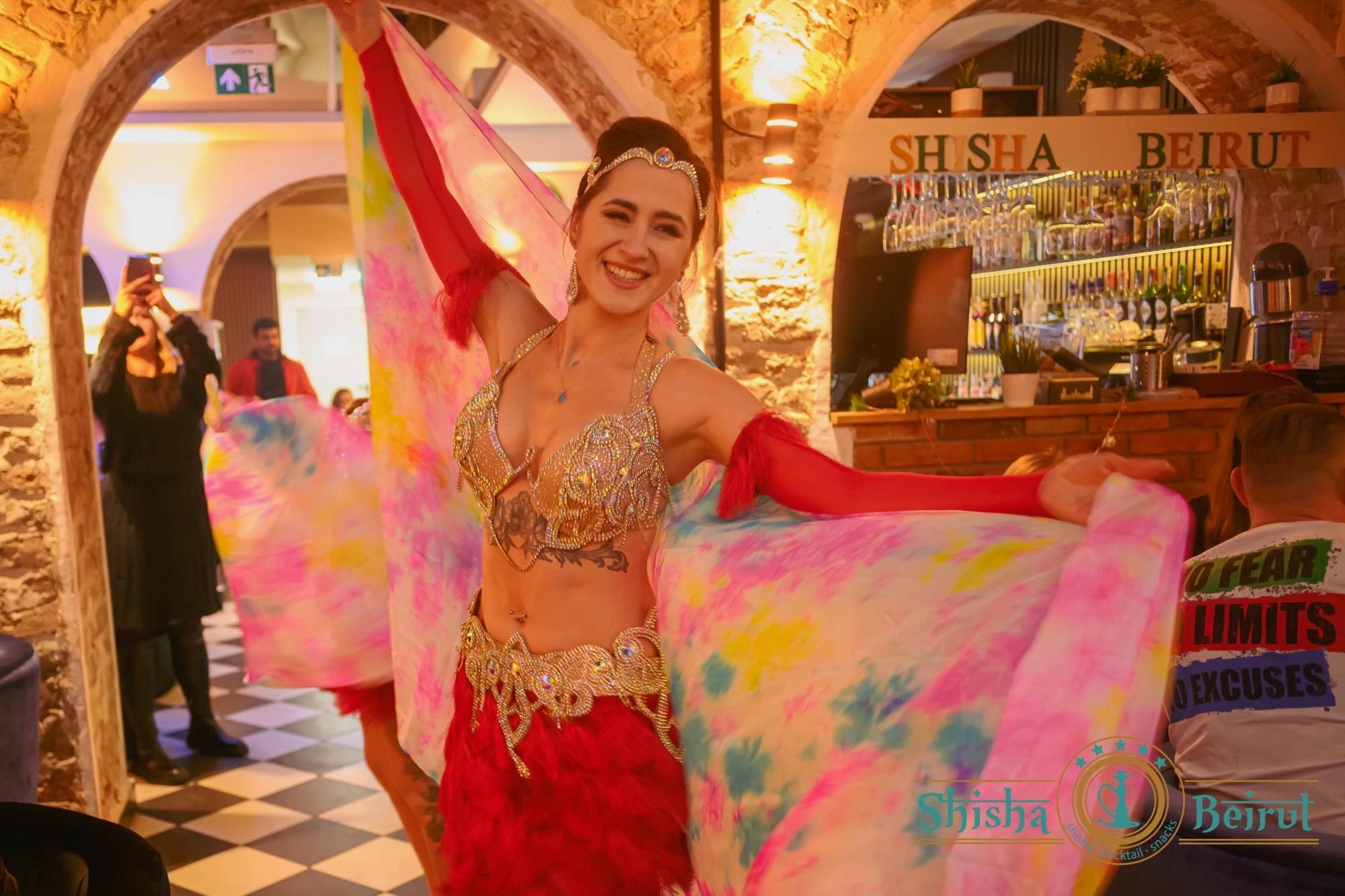 Kinga z duetu Wahatan tańczy z kolorowym woalem w restauracji z kamiennymi łukami