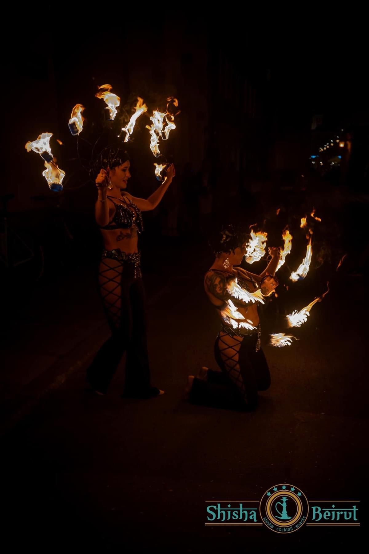Dramatyczny pokaz ogniowy duetu Wahatan w ciemności — tancerki z wieloma płonącymi pochodniami