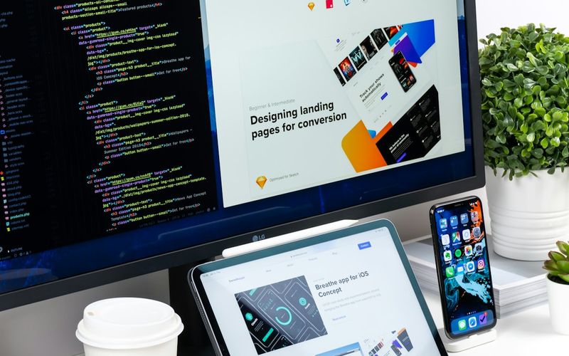 Web developer coding on multiple monitors with website design