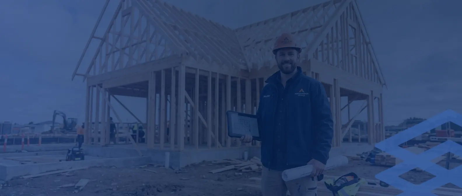 Builder holding plans in front of a house under construction
