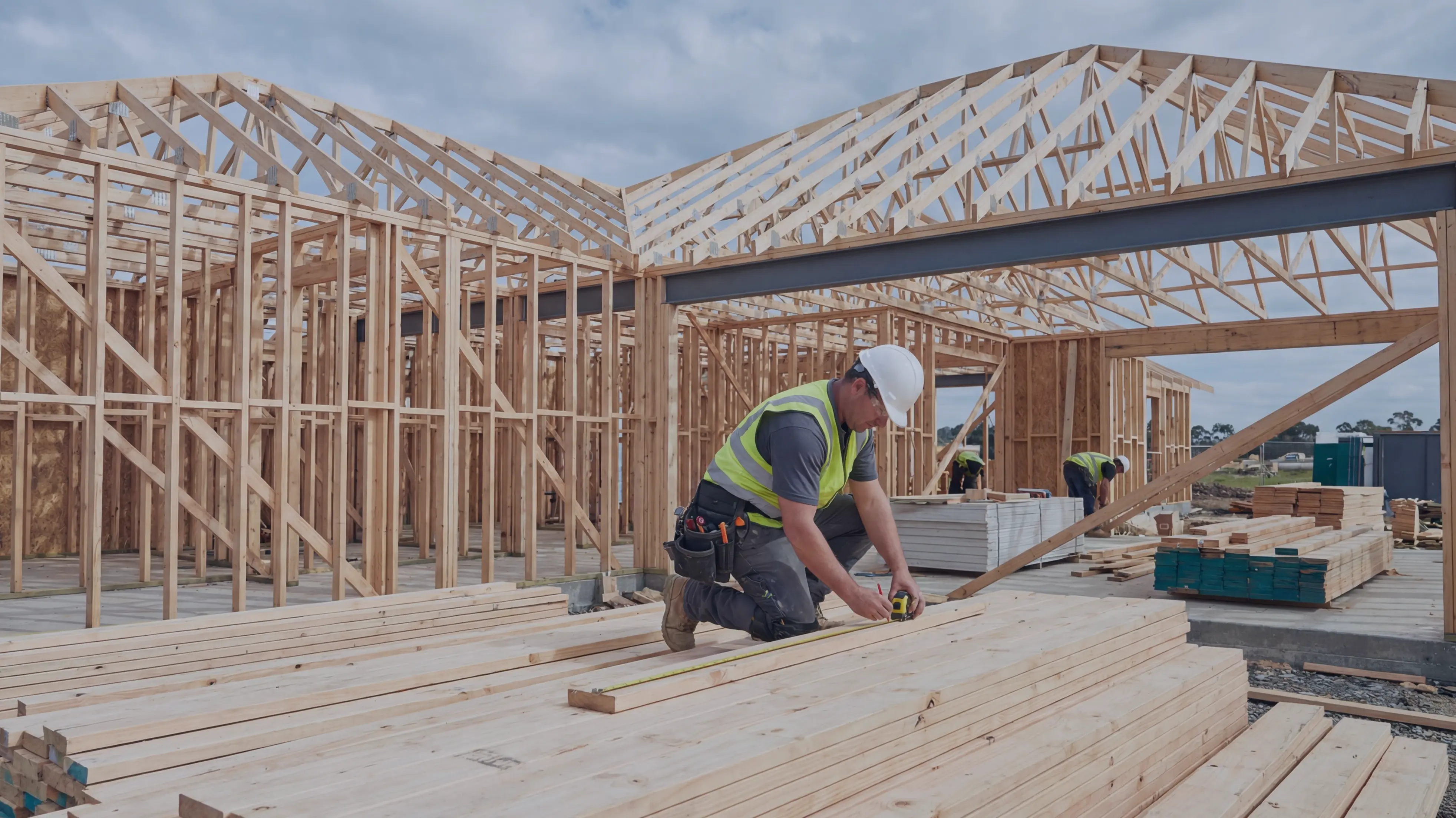 Construction worker measuring lumber at a residential framing site
