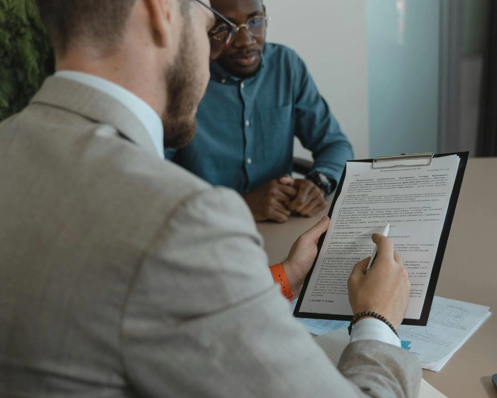 Home builder and advisor reviewing a contract during a dispute resolution discussion.