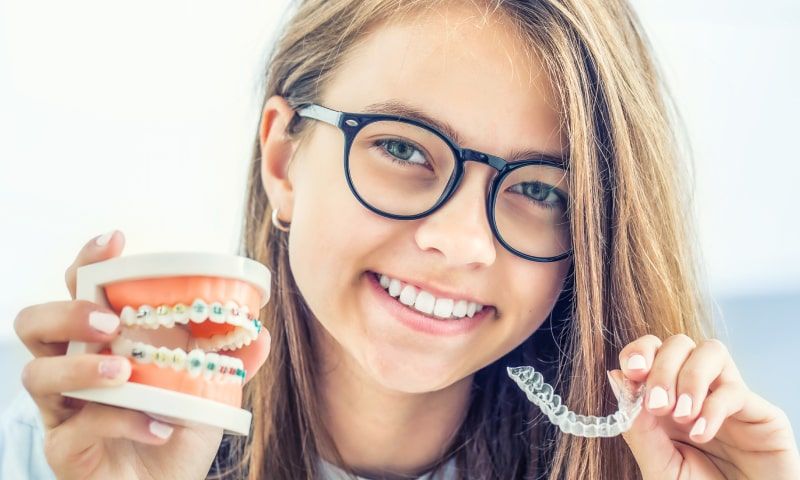 lady showing traditional braces model and Invisalign®