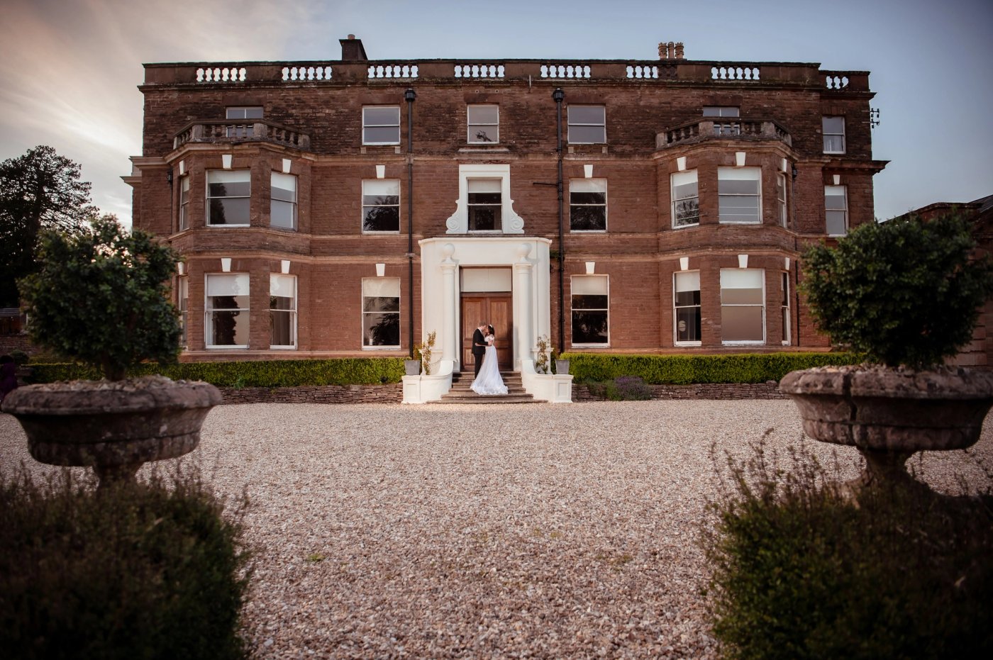 Nathan and Nastashia kiss on the steps of the manor house at Bredenbury Court Barns at dusk