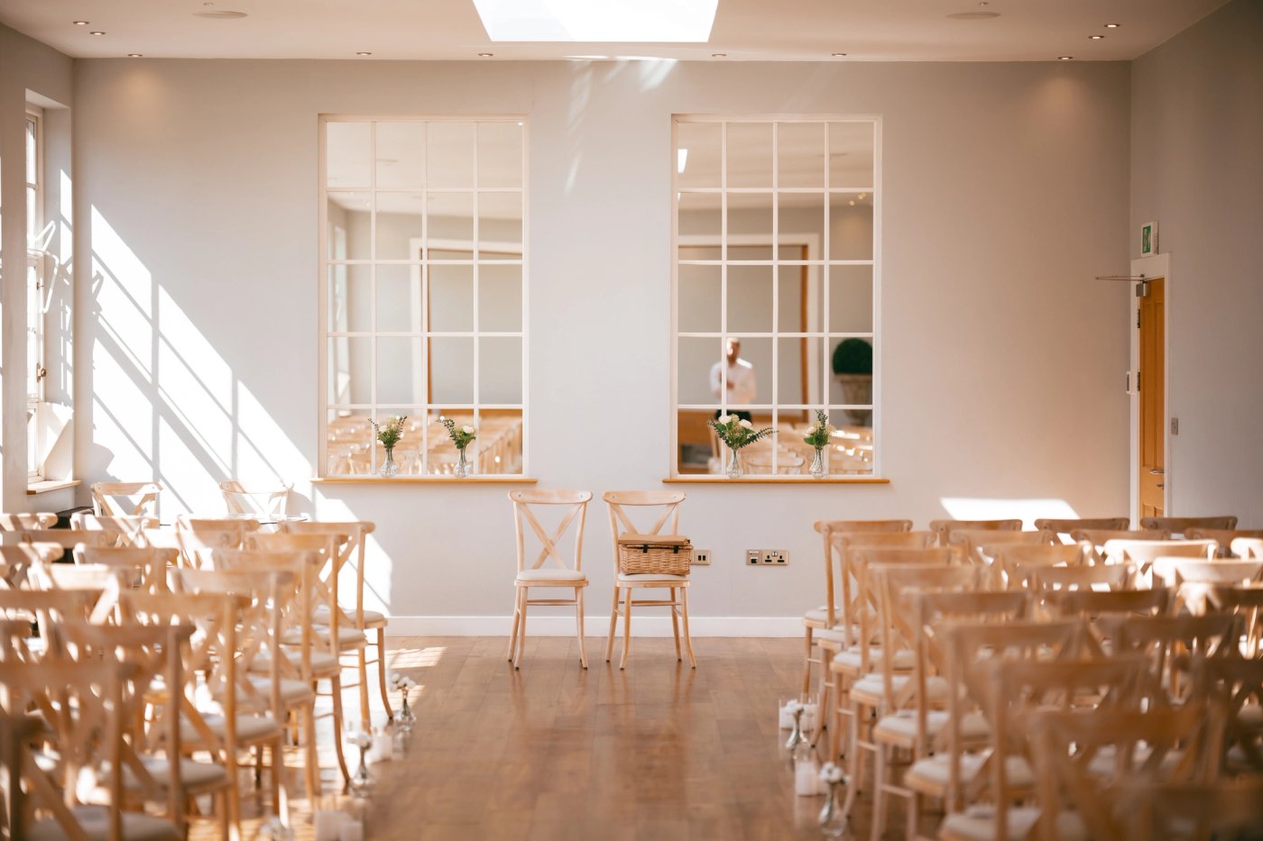 Ceremony room set up with cross-back chairs and white flowers at Bredenbury Court Barns