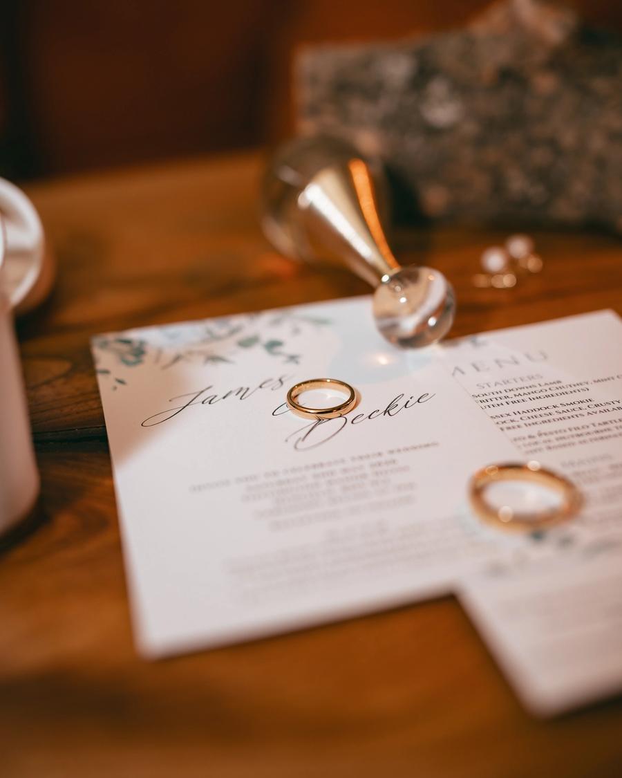 Wedding rings resting on the invitation, photographed by Pixton Media