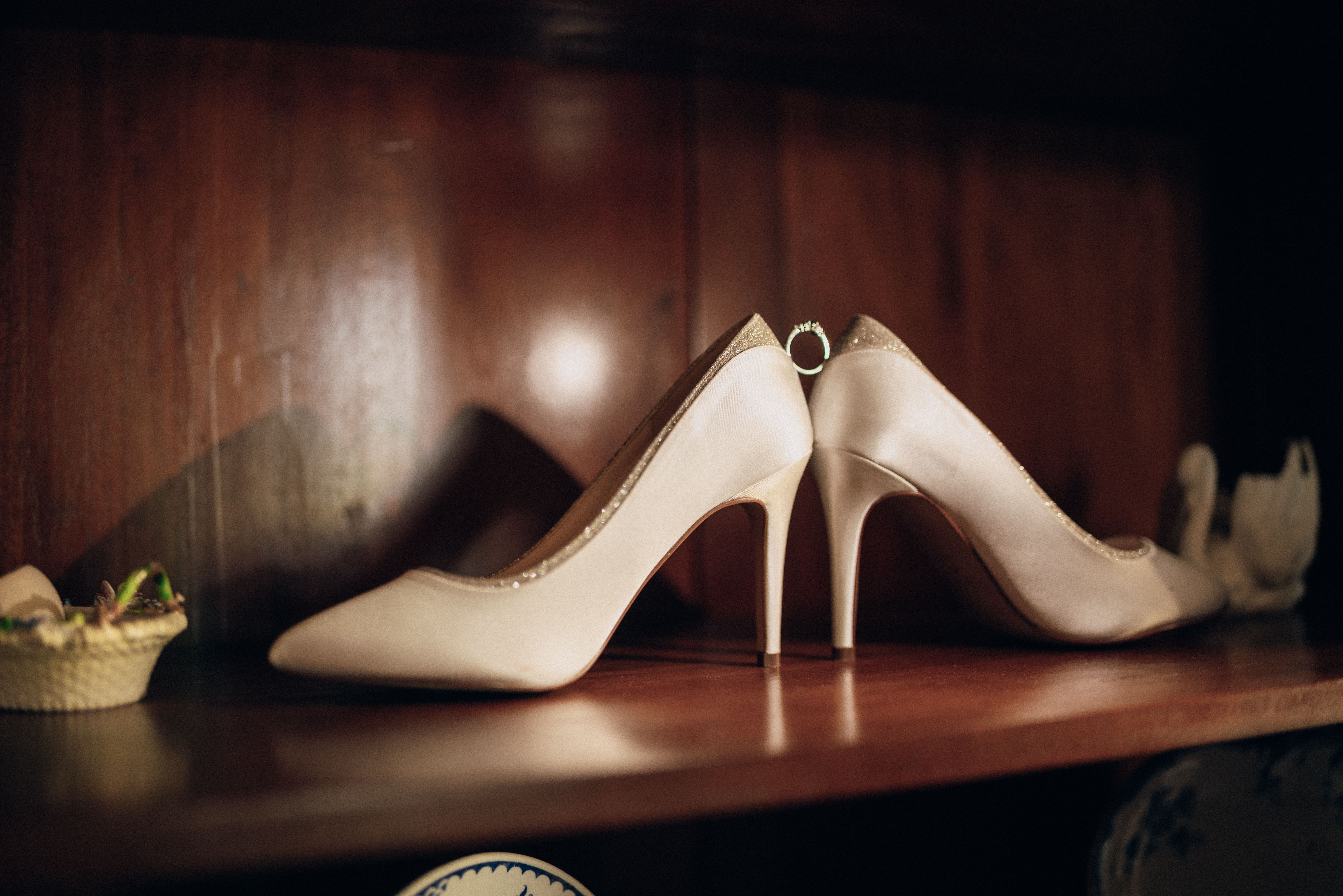 Bride's ivory heels on a wooden shelf, photographed by Pixton Media